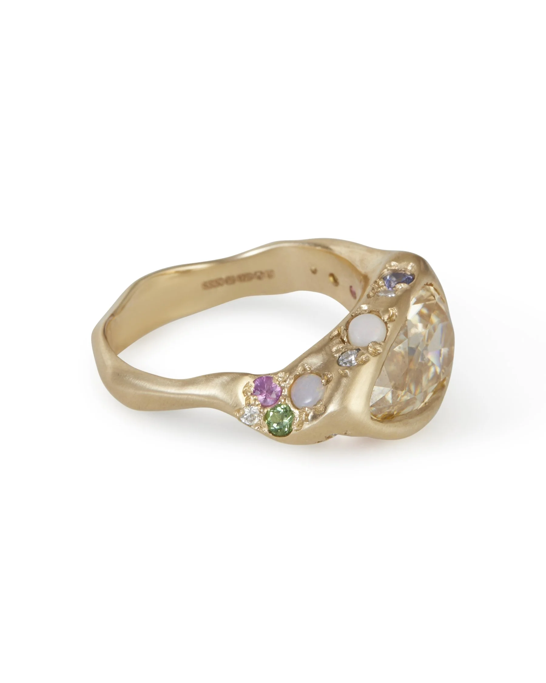 A pear shaped honey colours stones set east-west in a molten gold ring with colourful side stones
