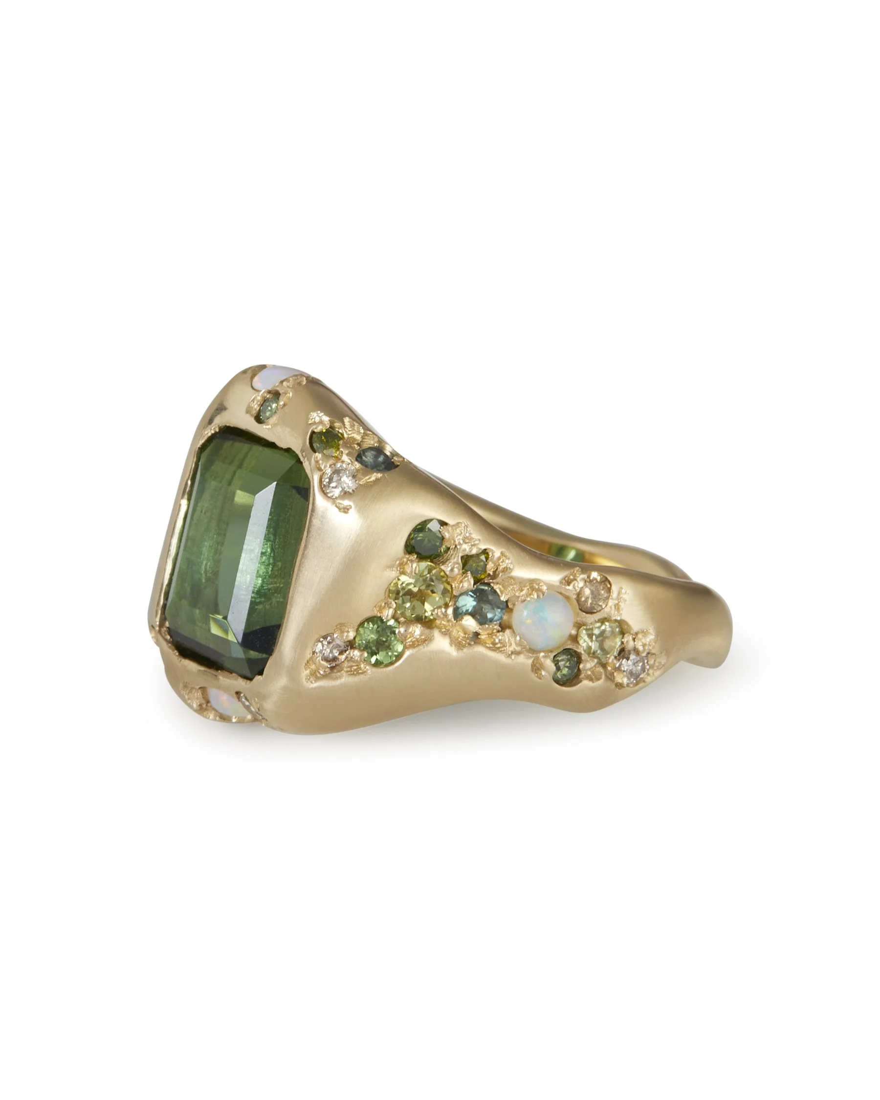 A large green stone ring with intricate green side stone details in molten gold