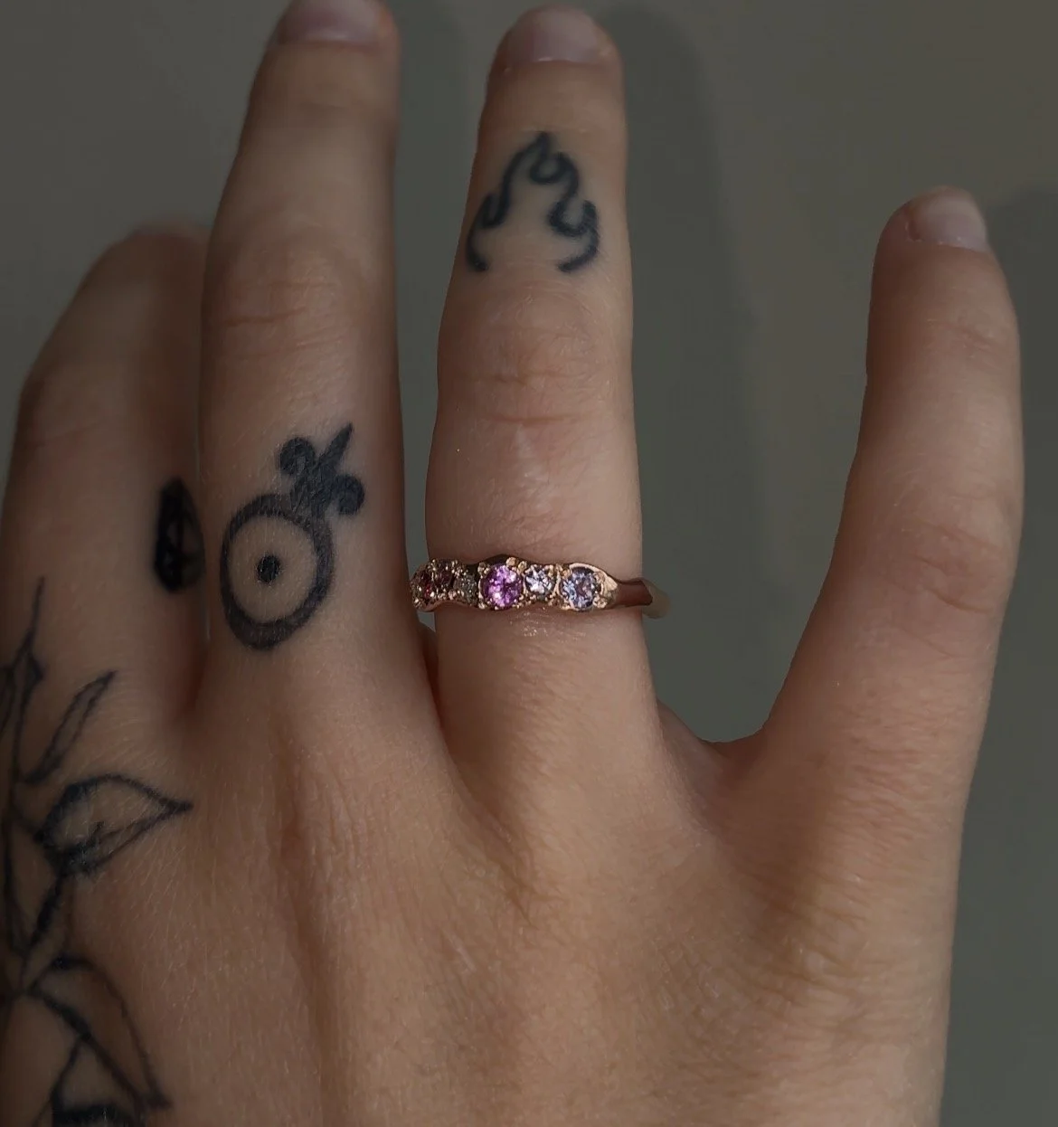 A molten red gold ring with pink gemstones photographed on a hand