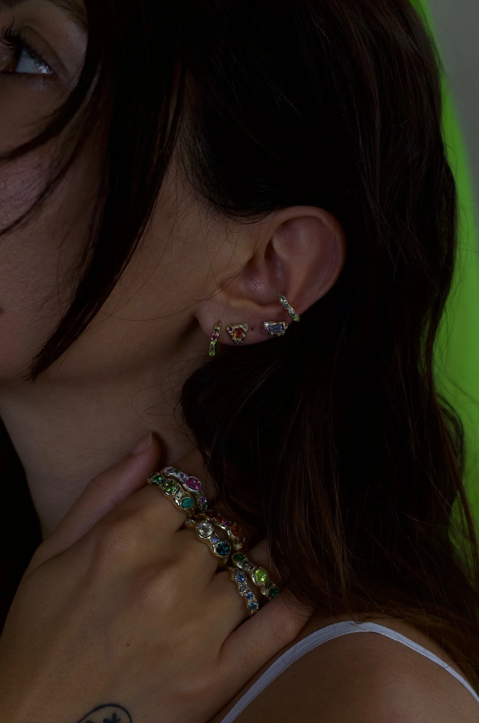 the side of a woman's head, wearing jewels on her hands and ears