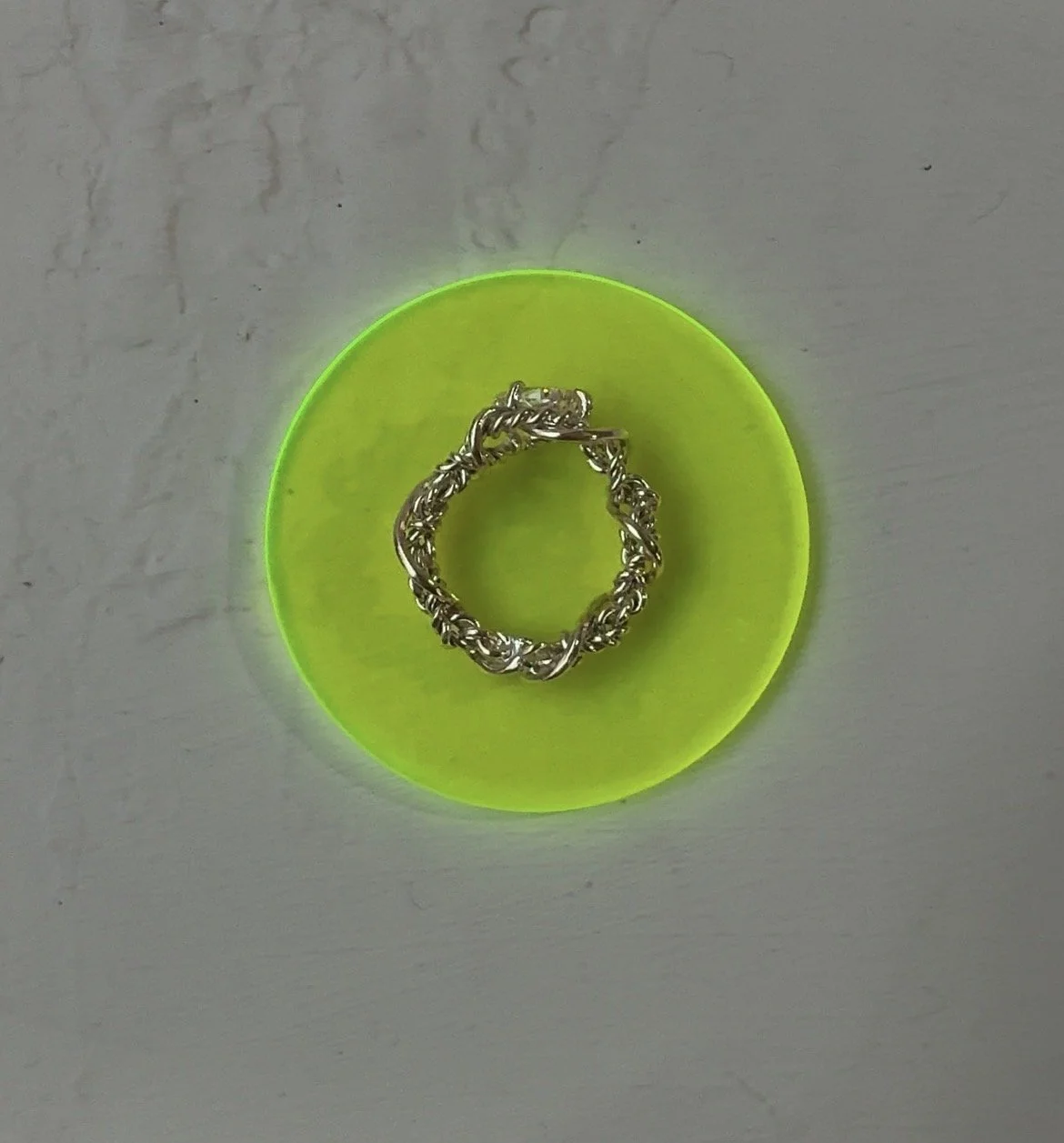 a yellow gold rope ring laid on neon acrylic
