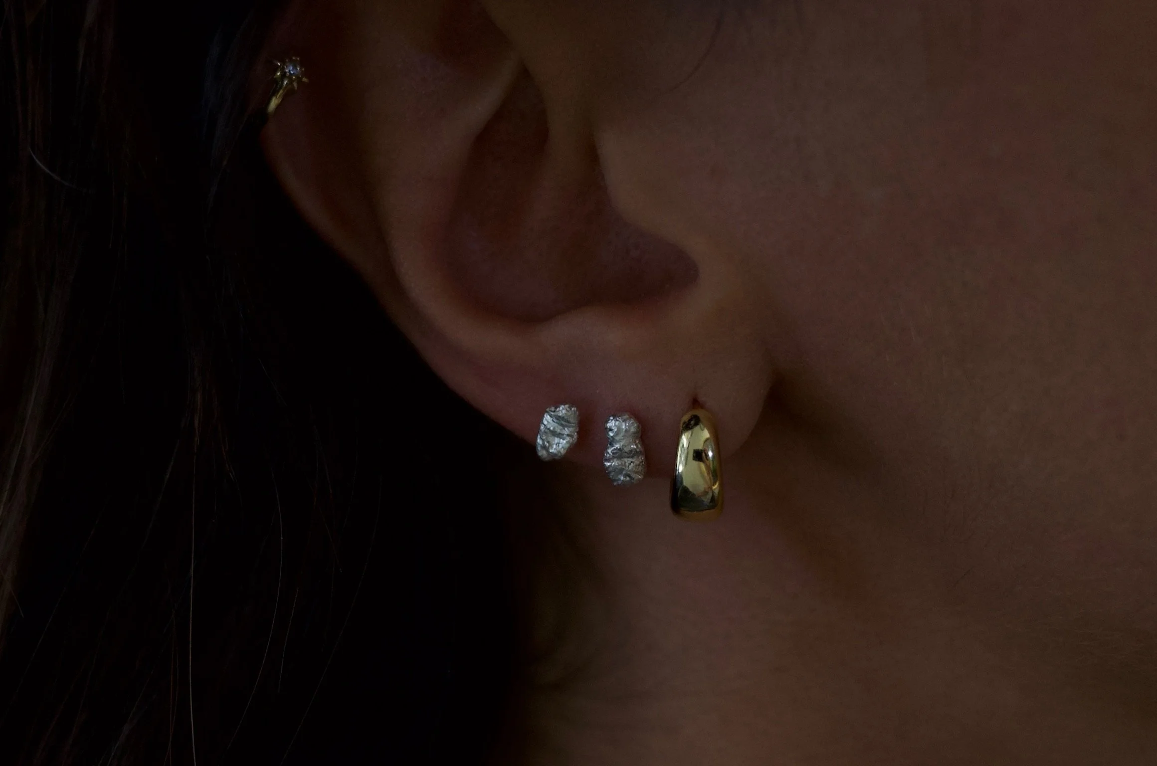 Textured sterling silver studs. The studs are mismatched and in an ear