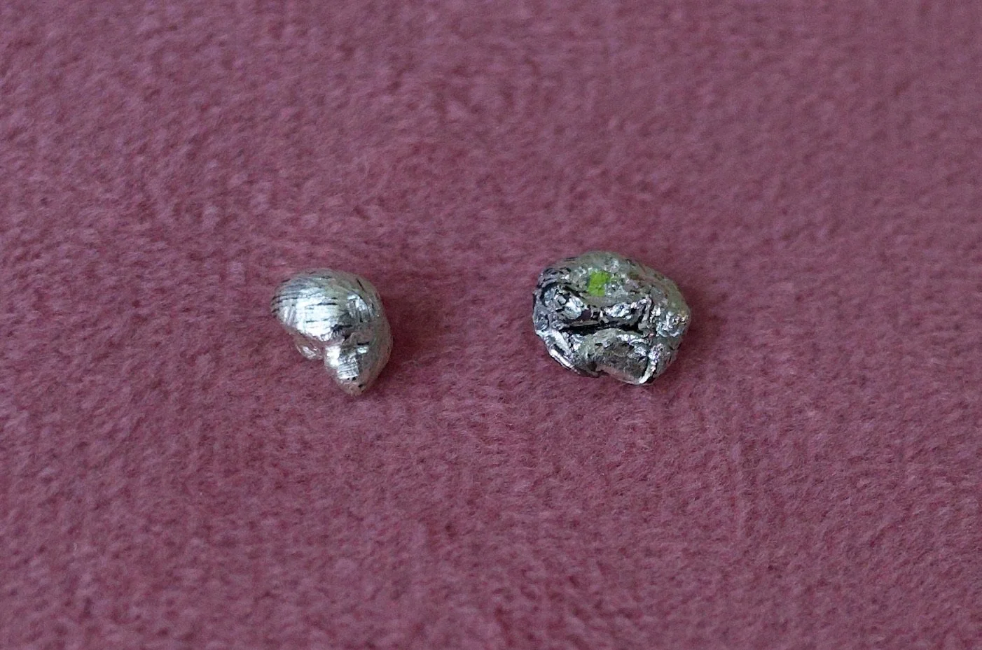 Textured sterling silver studs with a neon green stone in one stud. The studs are mismatched