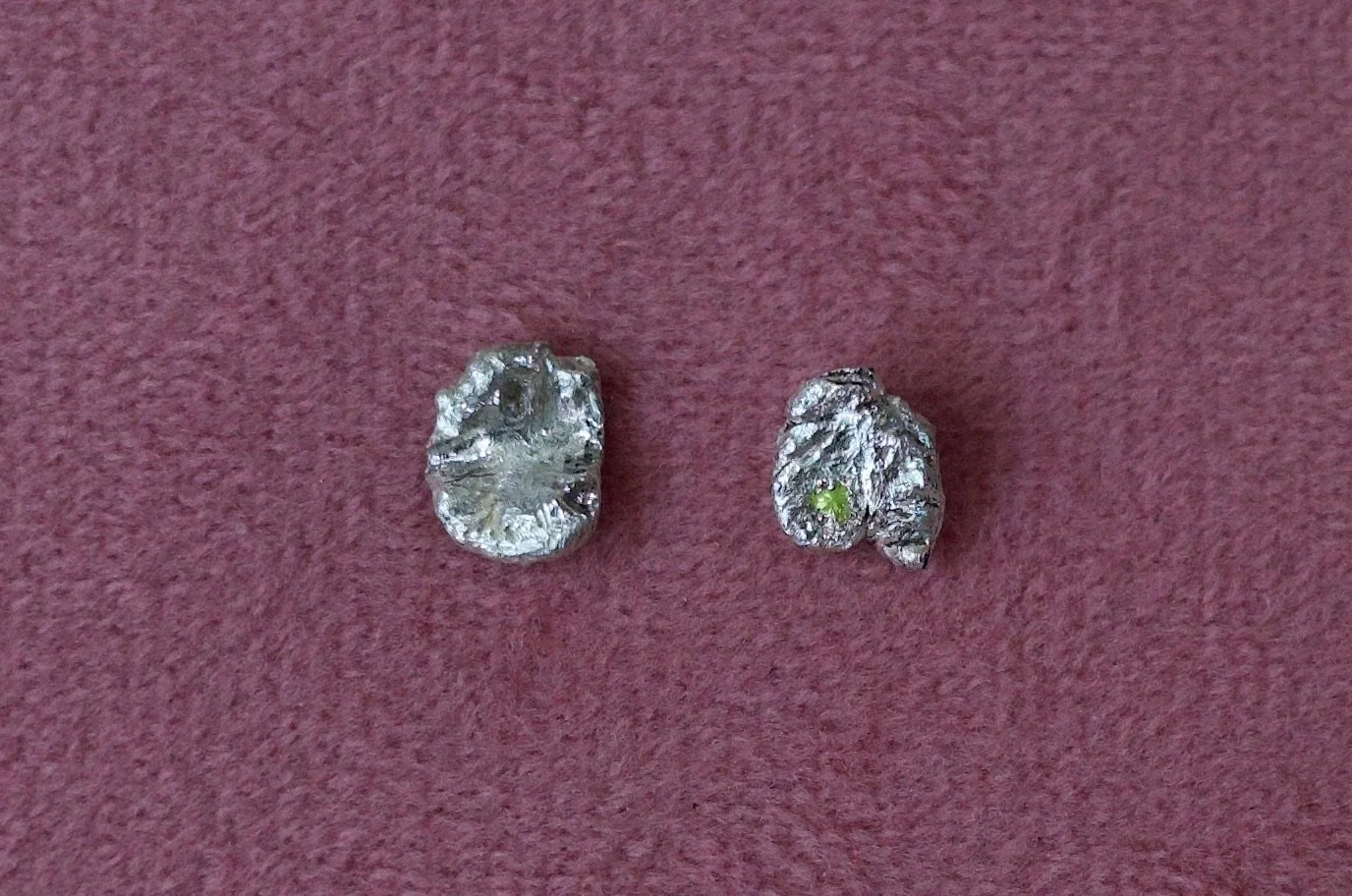 Textured sterling silver studs with a neon green stone in one stud. The studs are mismatched