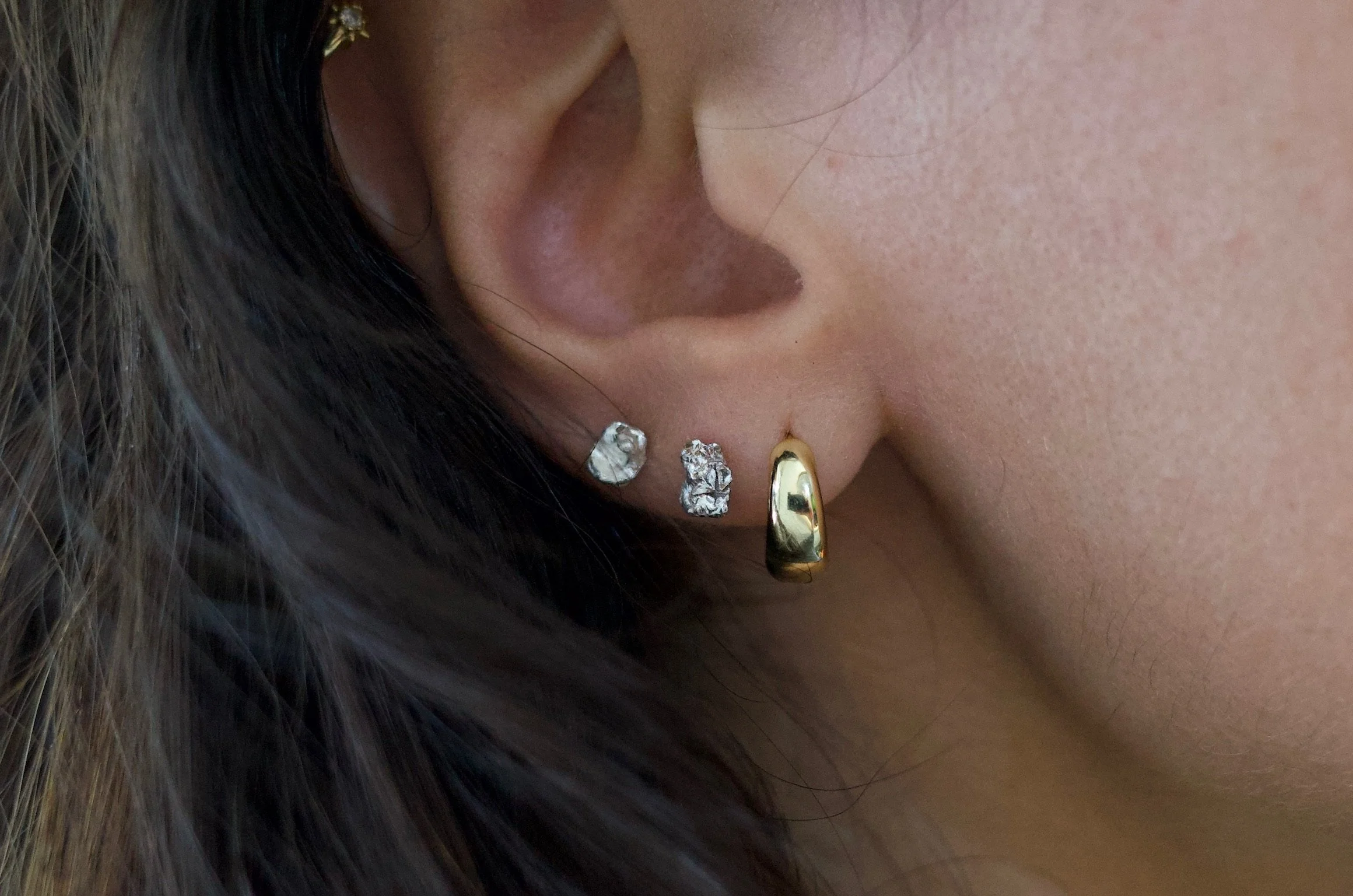 Textured sterling silver studs. The studs are mismatched and in an ear