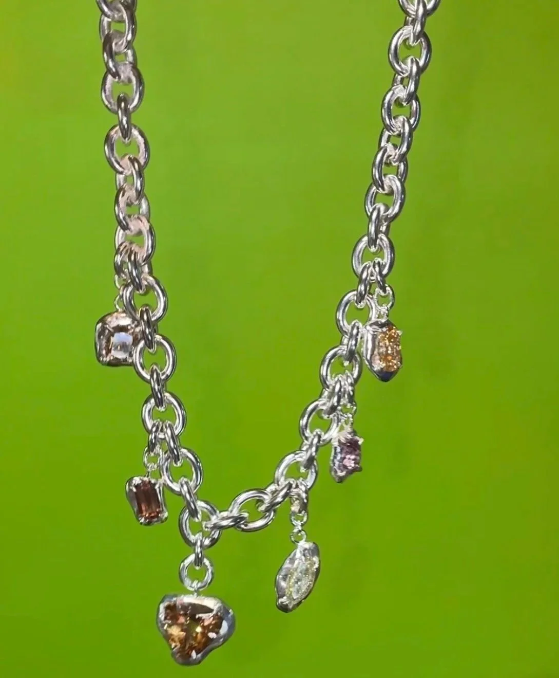 a huge silver necklace with brown gemstones on a green background