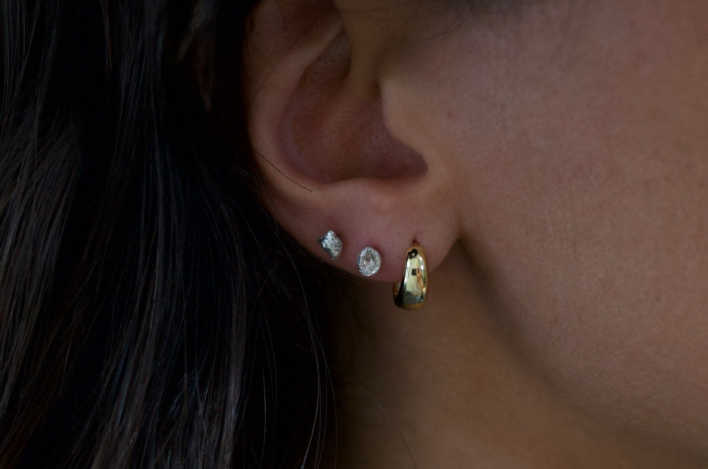 Textured sterling silver studs. The studs are mismatched and in an ear