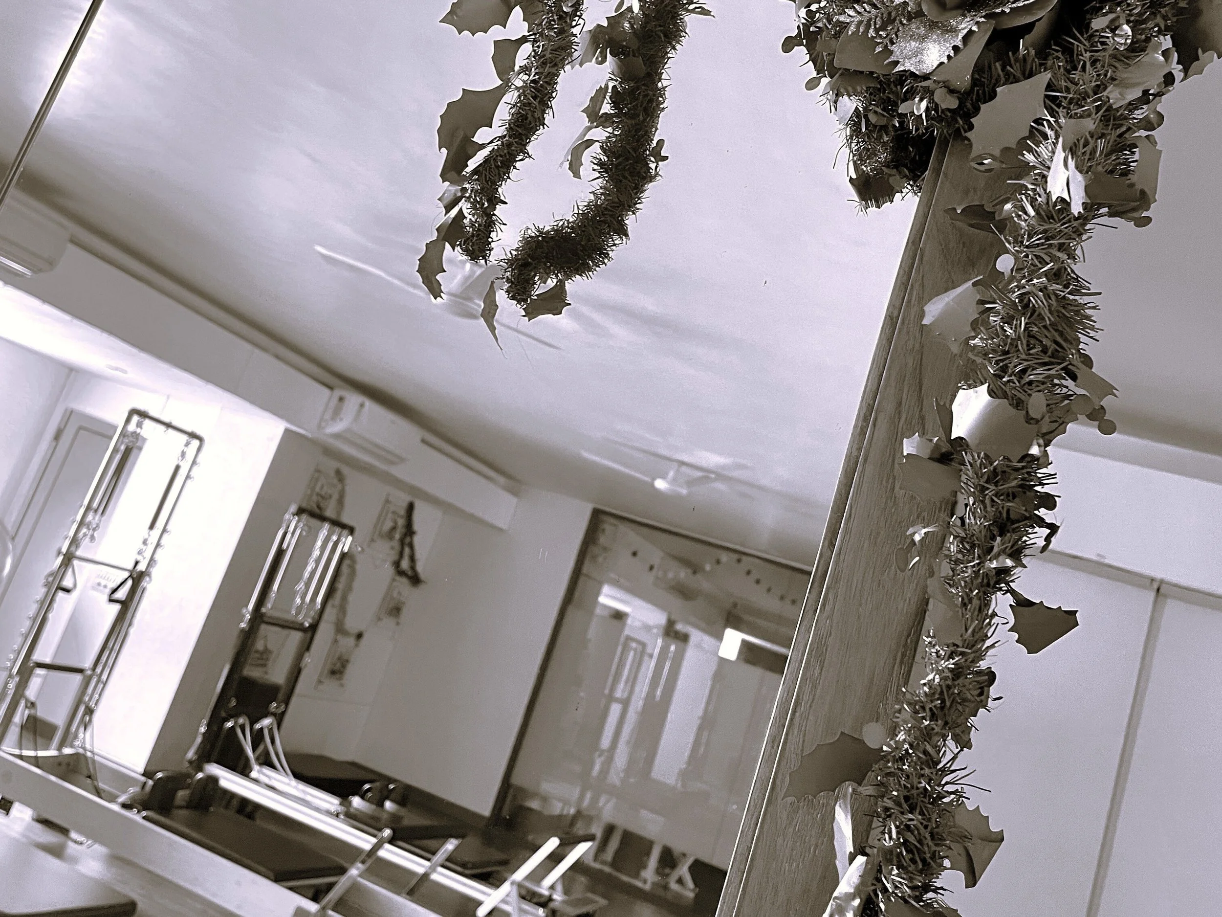 Christmas decorations over a studio doorway, with Pilates reformers below.