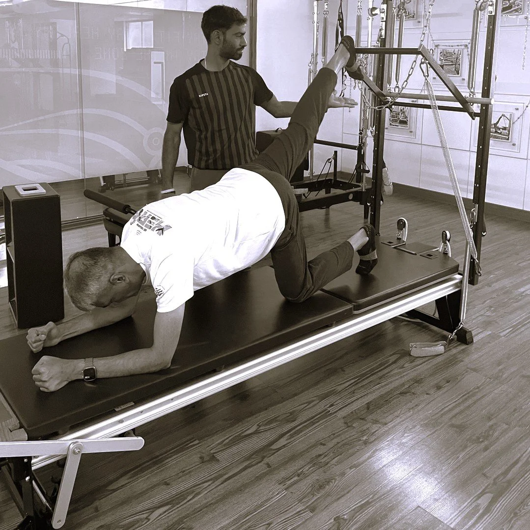 Male client doing Pilates on the Tower with instructor guiding