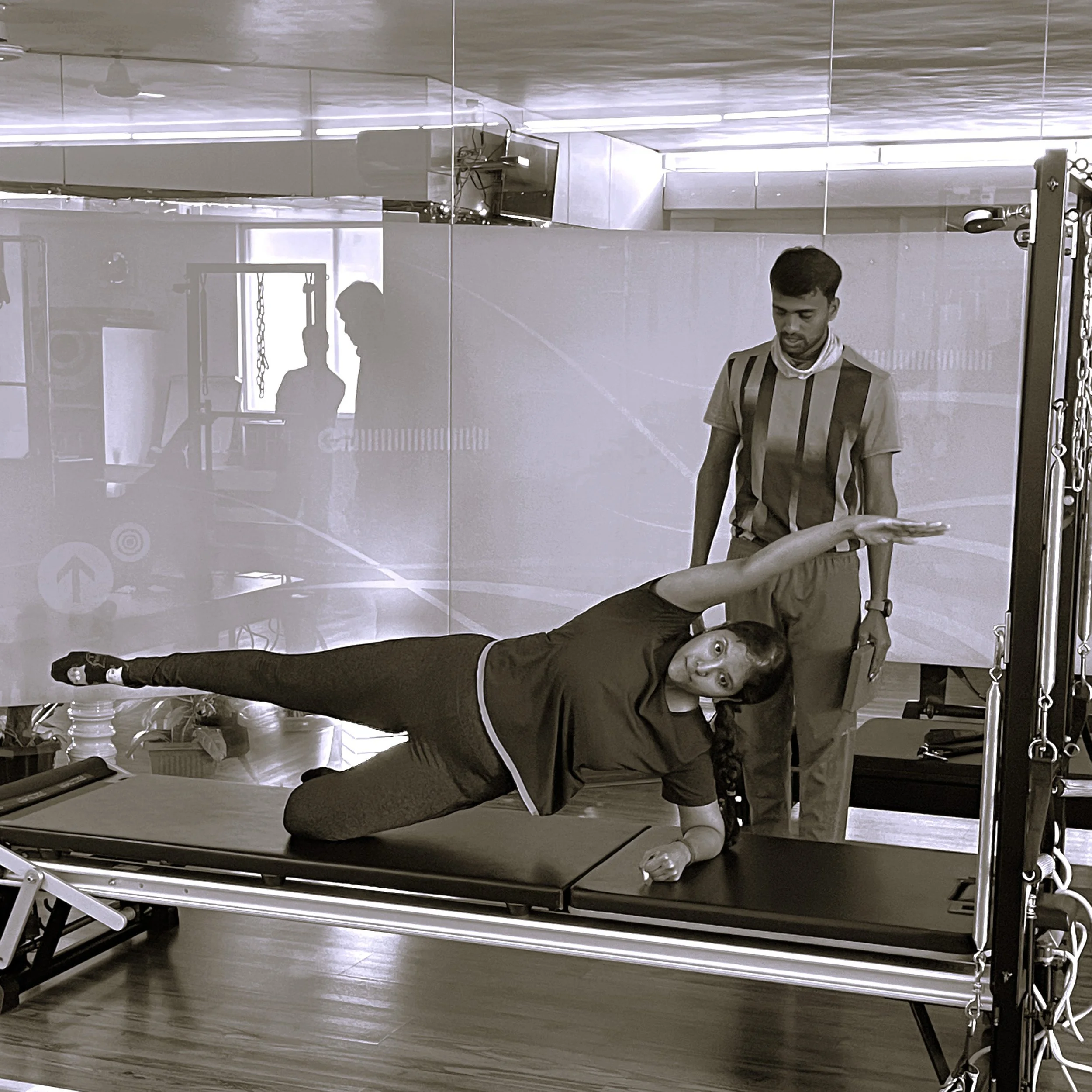 Pilates instructor guiding a client through a side-lying exercise on the Reformer at The Zone Mind and Body Studio, Bangalore
