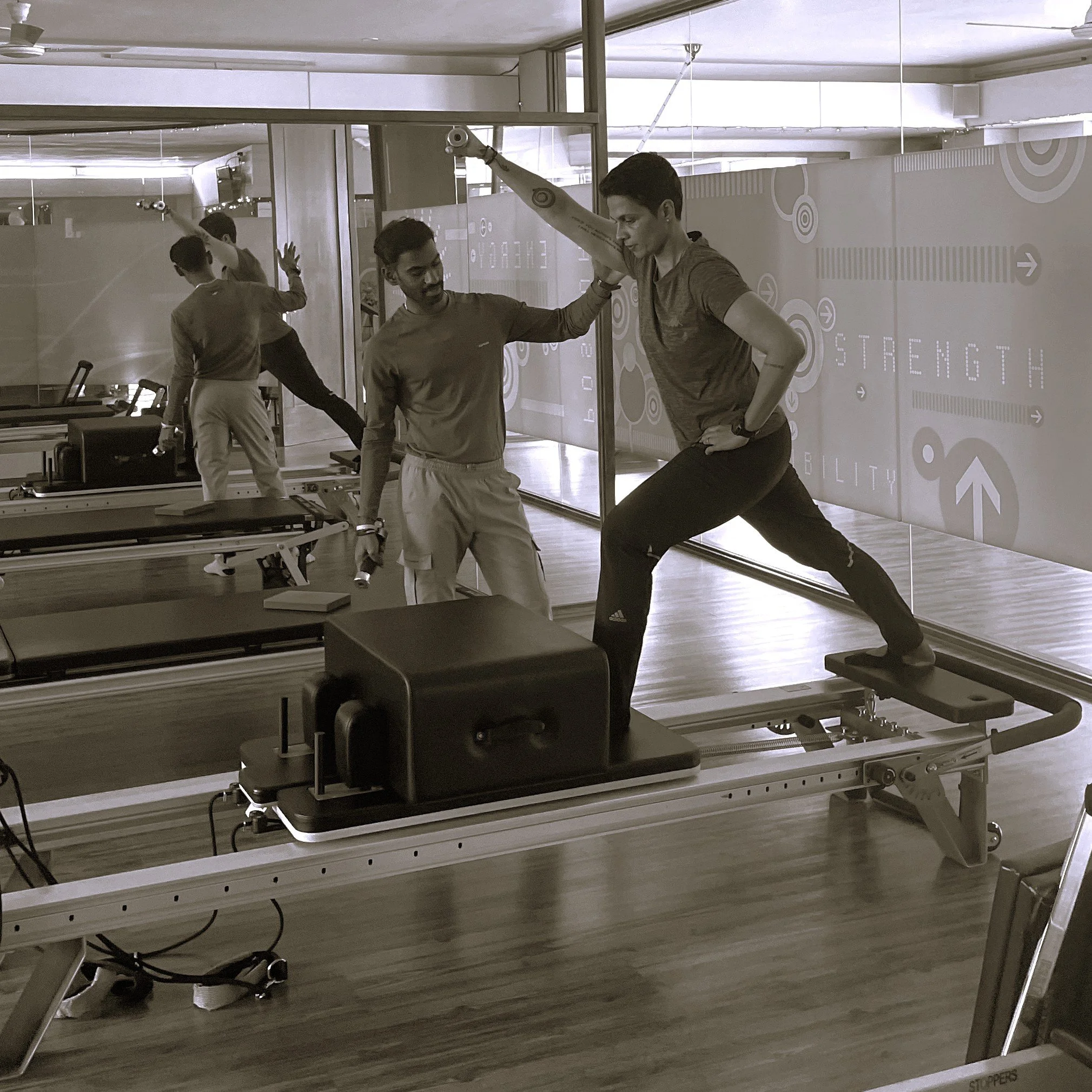 Woman standing on the Pilates reformer machine being instructed in a personal training session