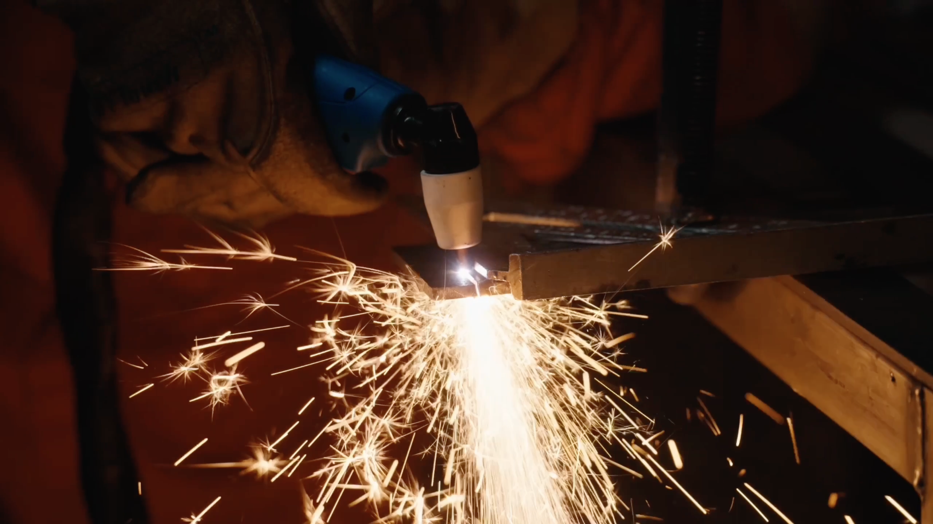 A person welding metal, sparks flying in all directions, in a workshop or construction setting.