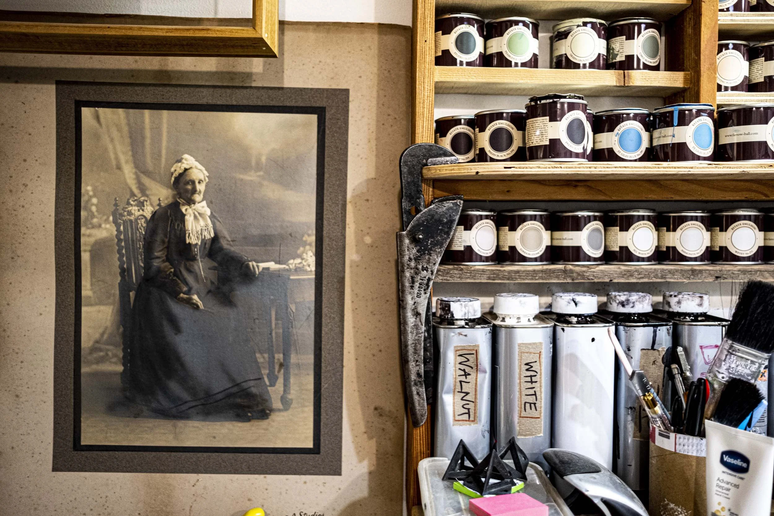 photograph of white Victorian woman on wall next to paint tins.jpg