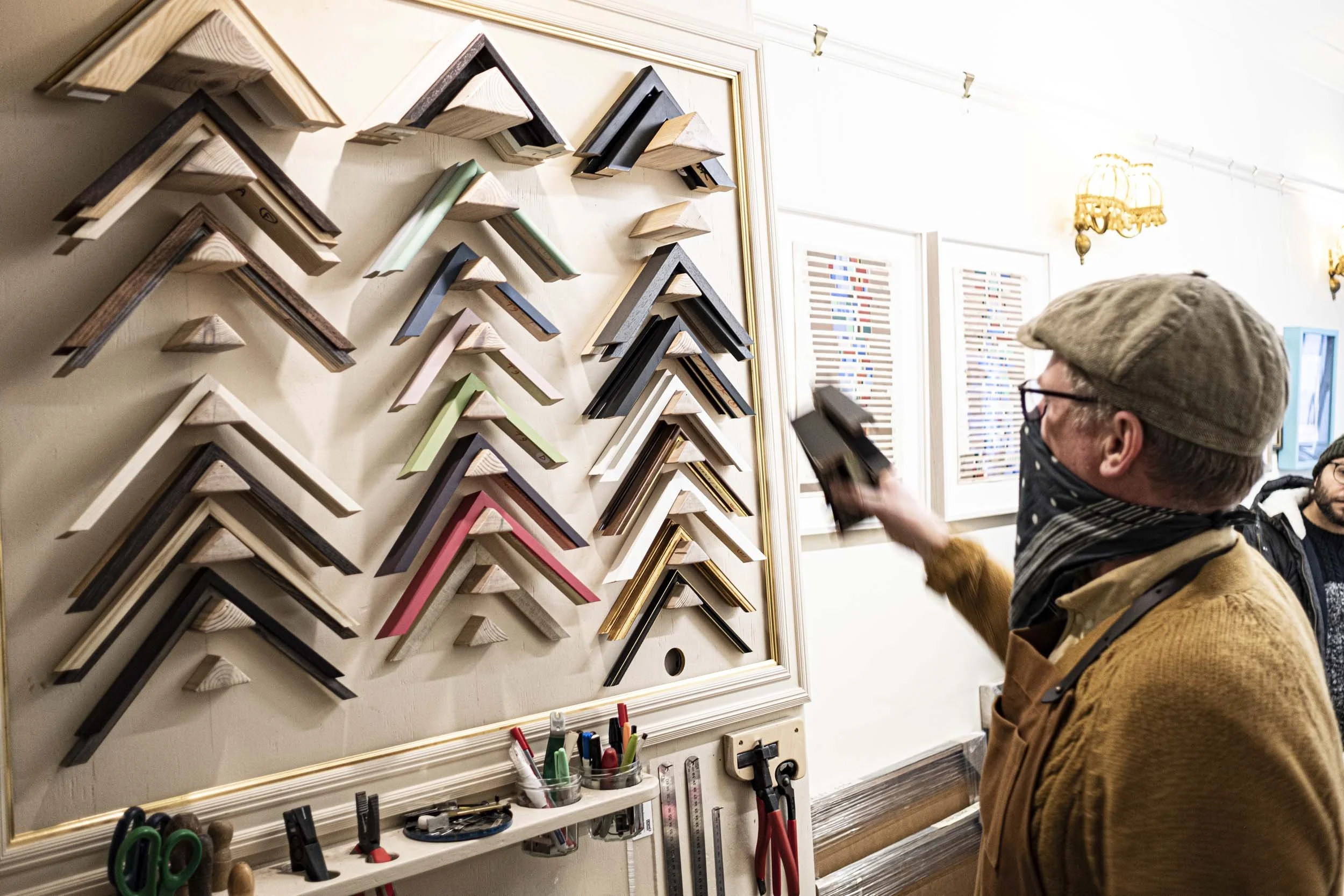 white male with mask over mouth and nose looking at wooden frame options.jpg