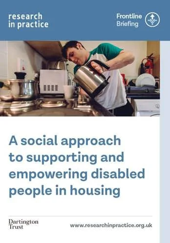 A disabled man pouring water from a kettle into a cup in his kitchen.