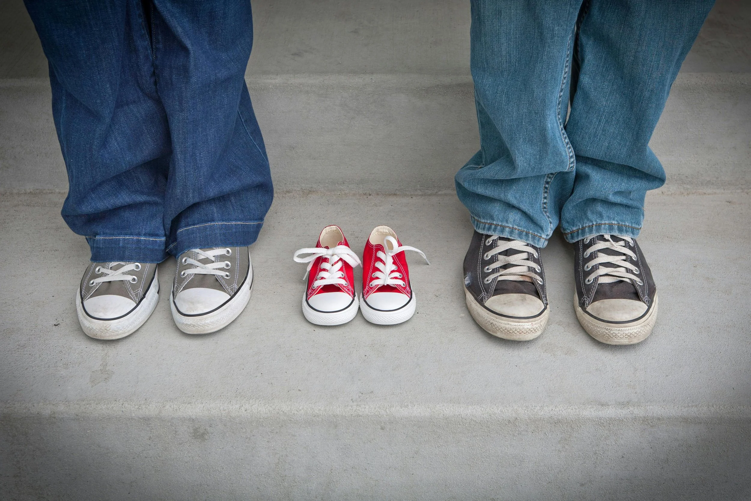 A LGBTQ+ couple who did fertility counselling in Toronto standing beside their baby's shoes