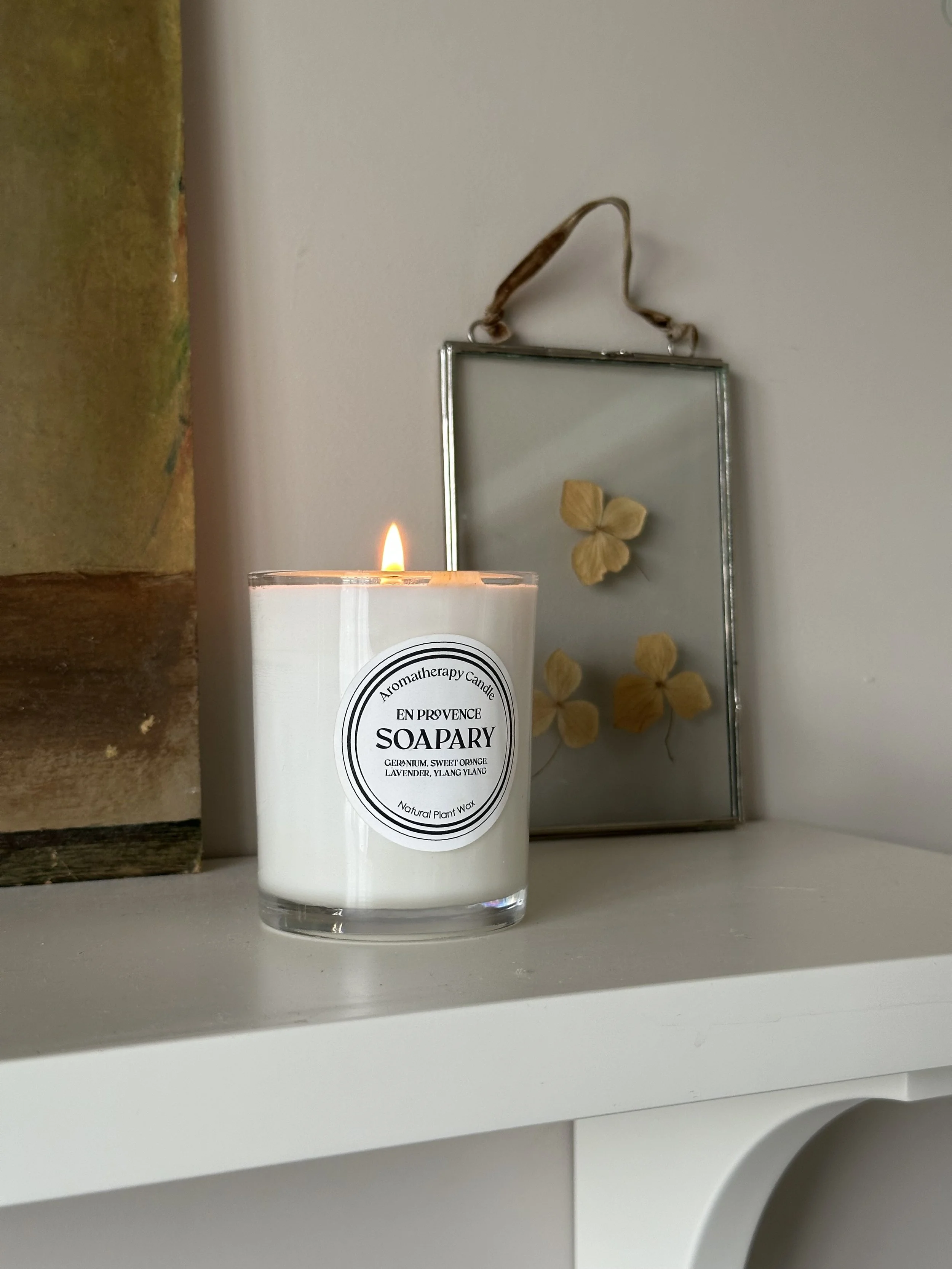 aromatherapy candle with flame on neutral shelf