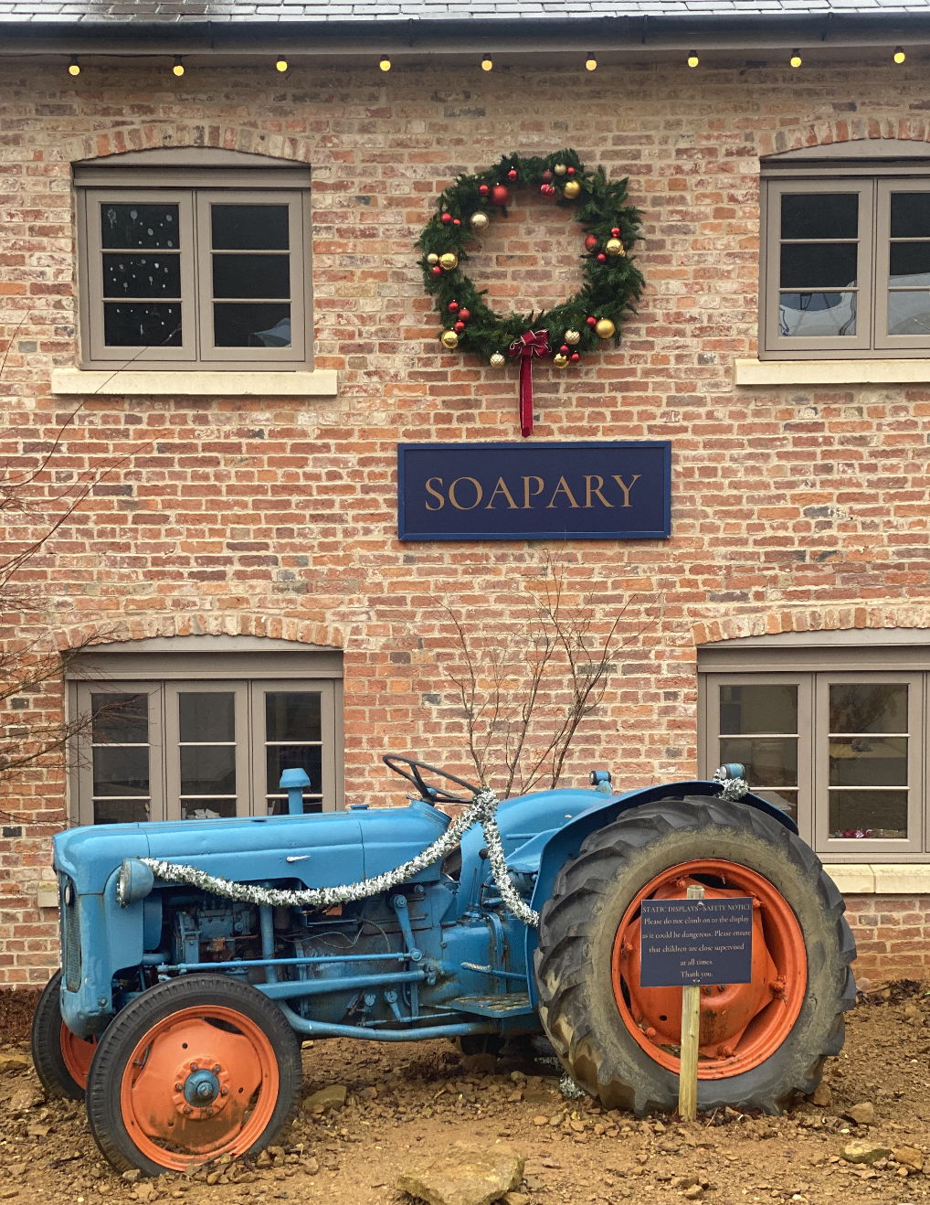 A shop front at Belvoir Retail Village with sign soapary, a vintage tractor in front and a Christmas garland on the wall