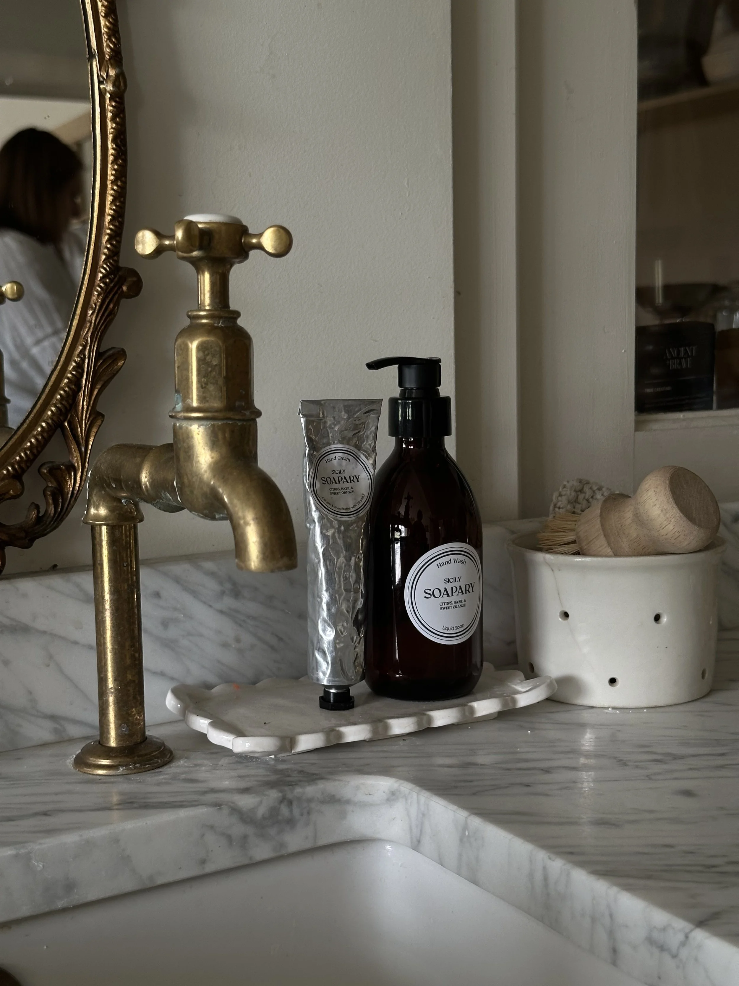 hadn't cream and hand wash at a sink with brass taps
