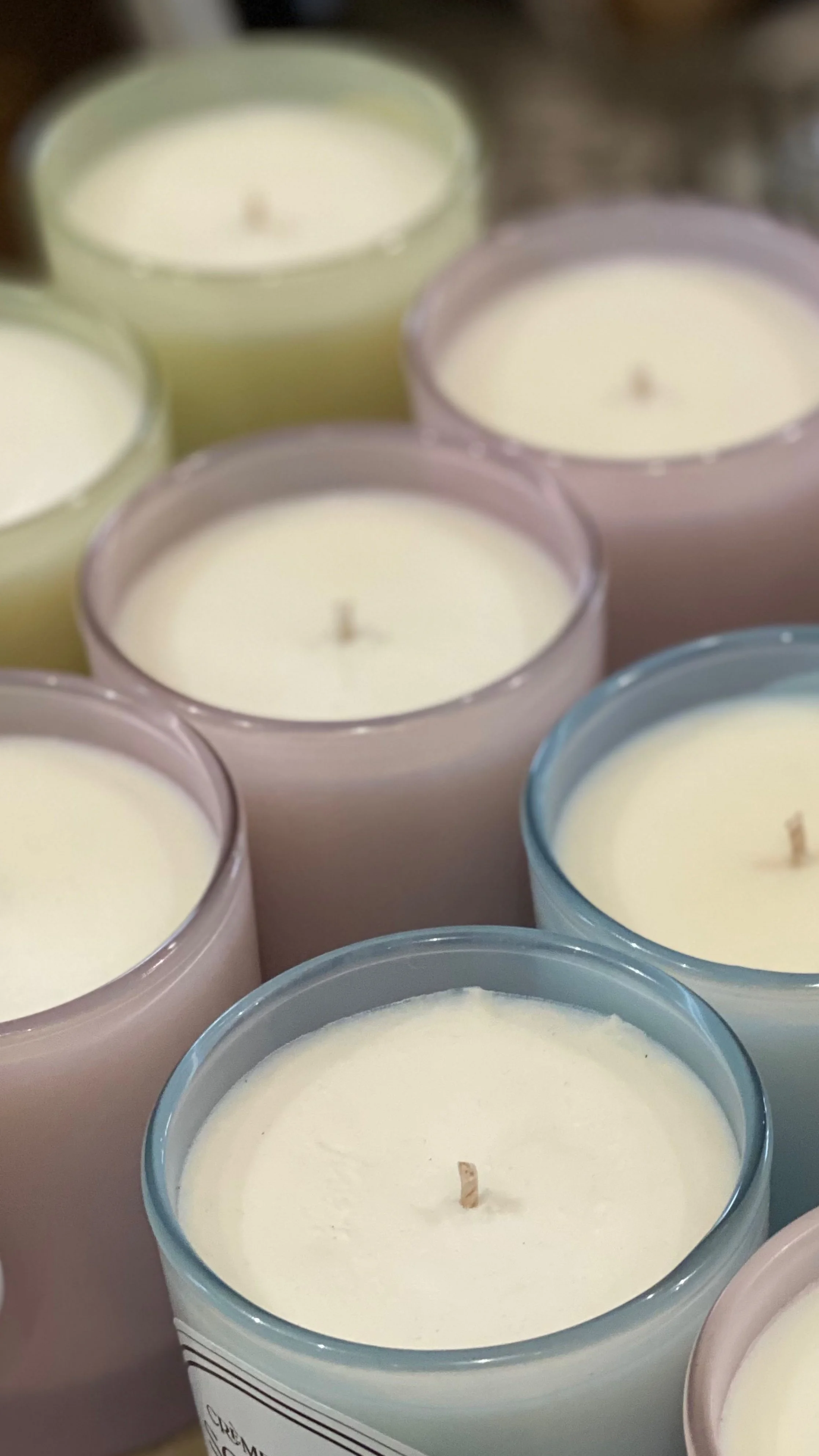 Close-up of multiple scented candles in glass containers with unlit wicks.