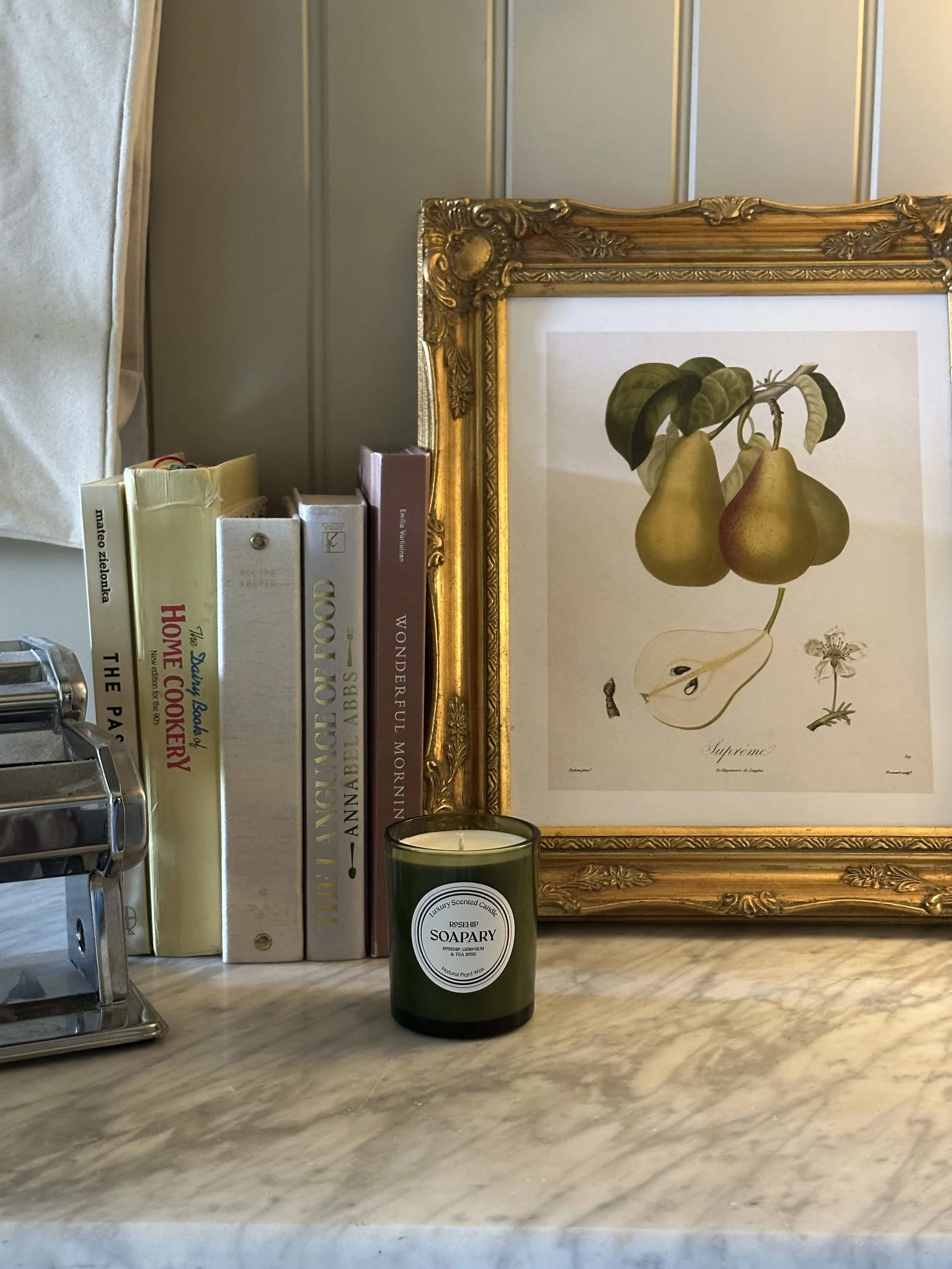 candle with books and artwork behind
