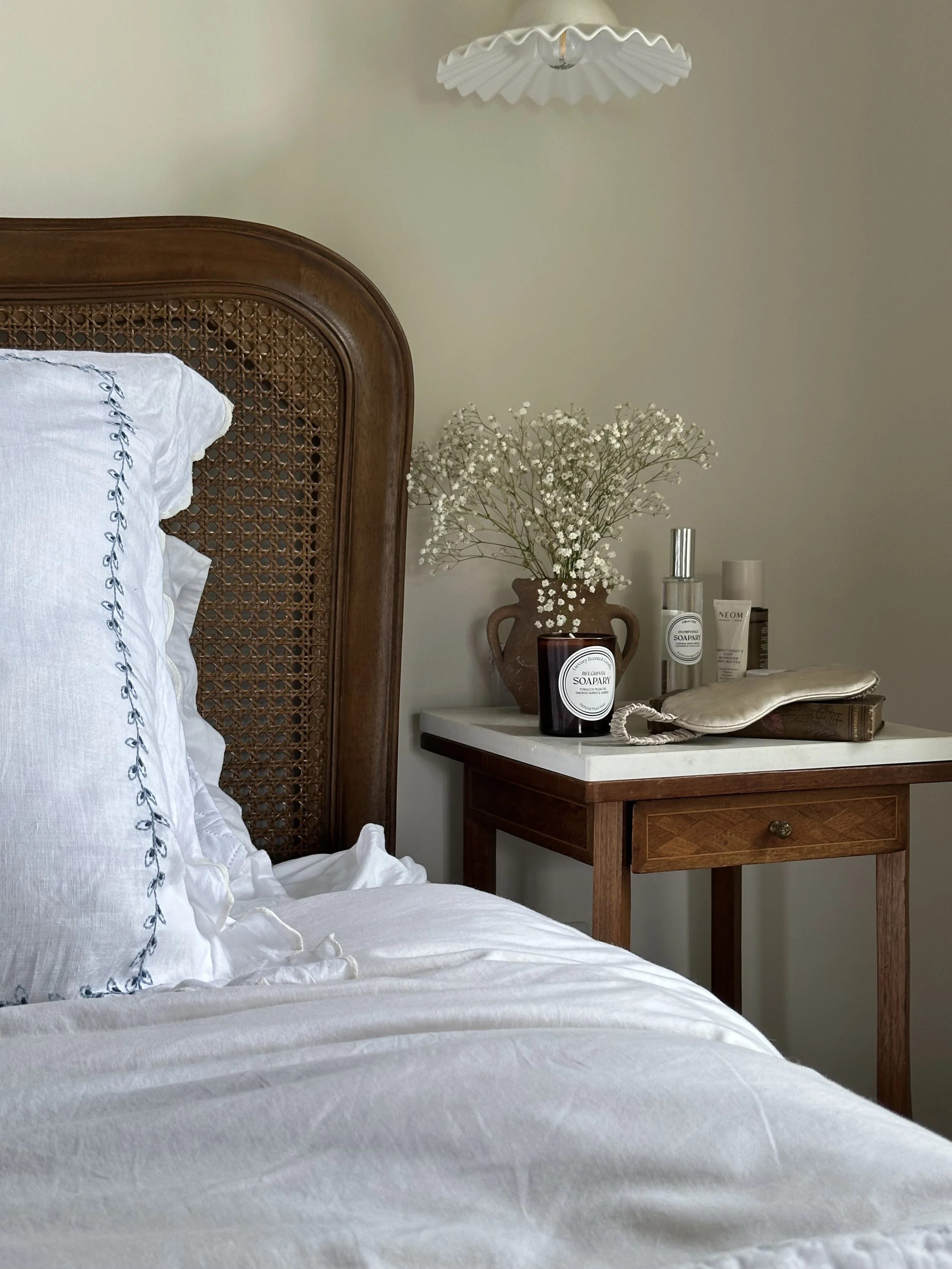 a beautiful bed with candle and pillow. mist on the bedside table