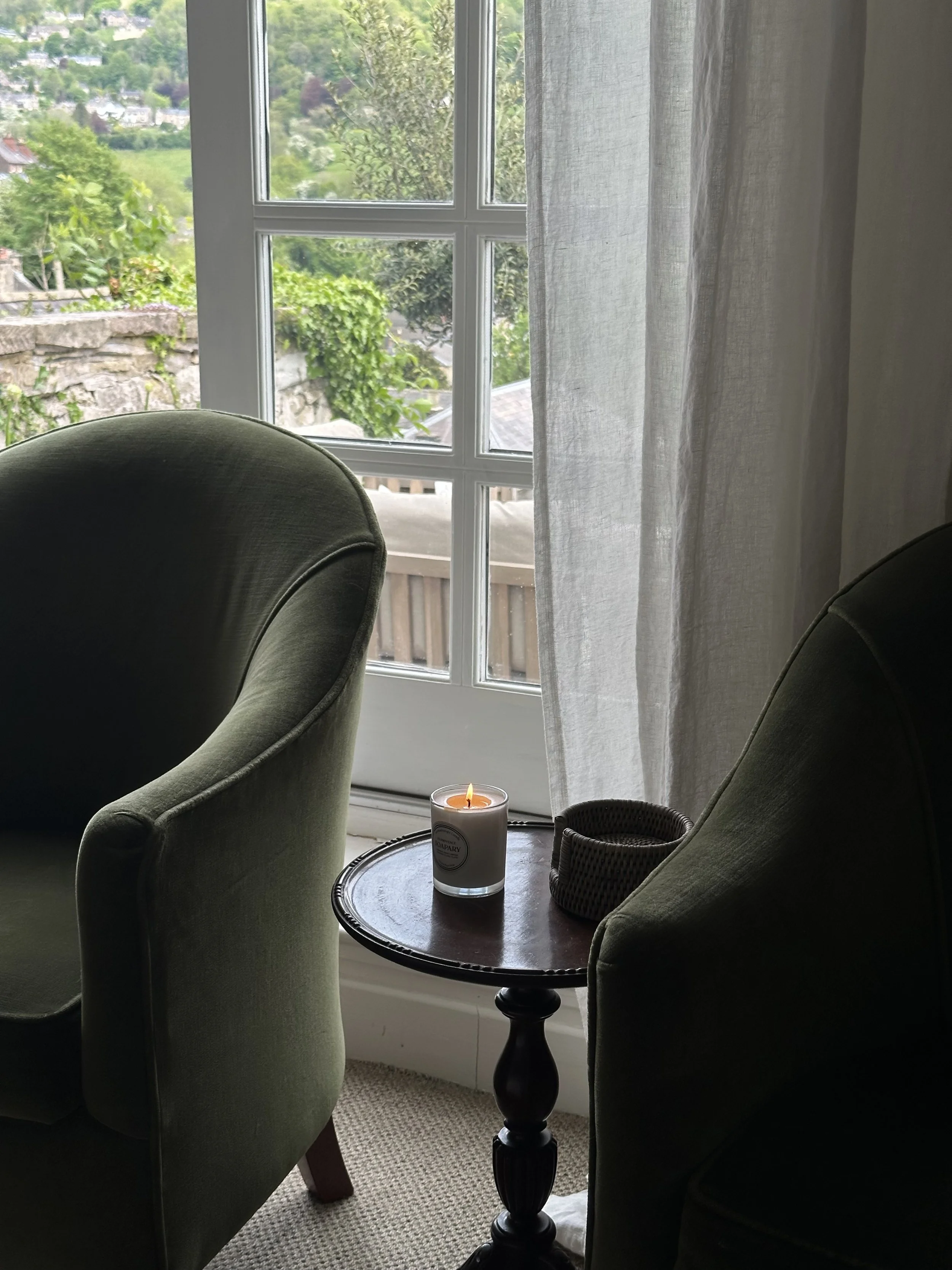 lovely lit candle next to a velvet green armchair for a perfect evening