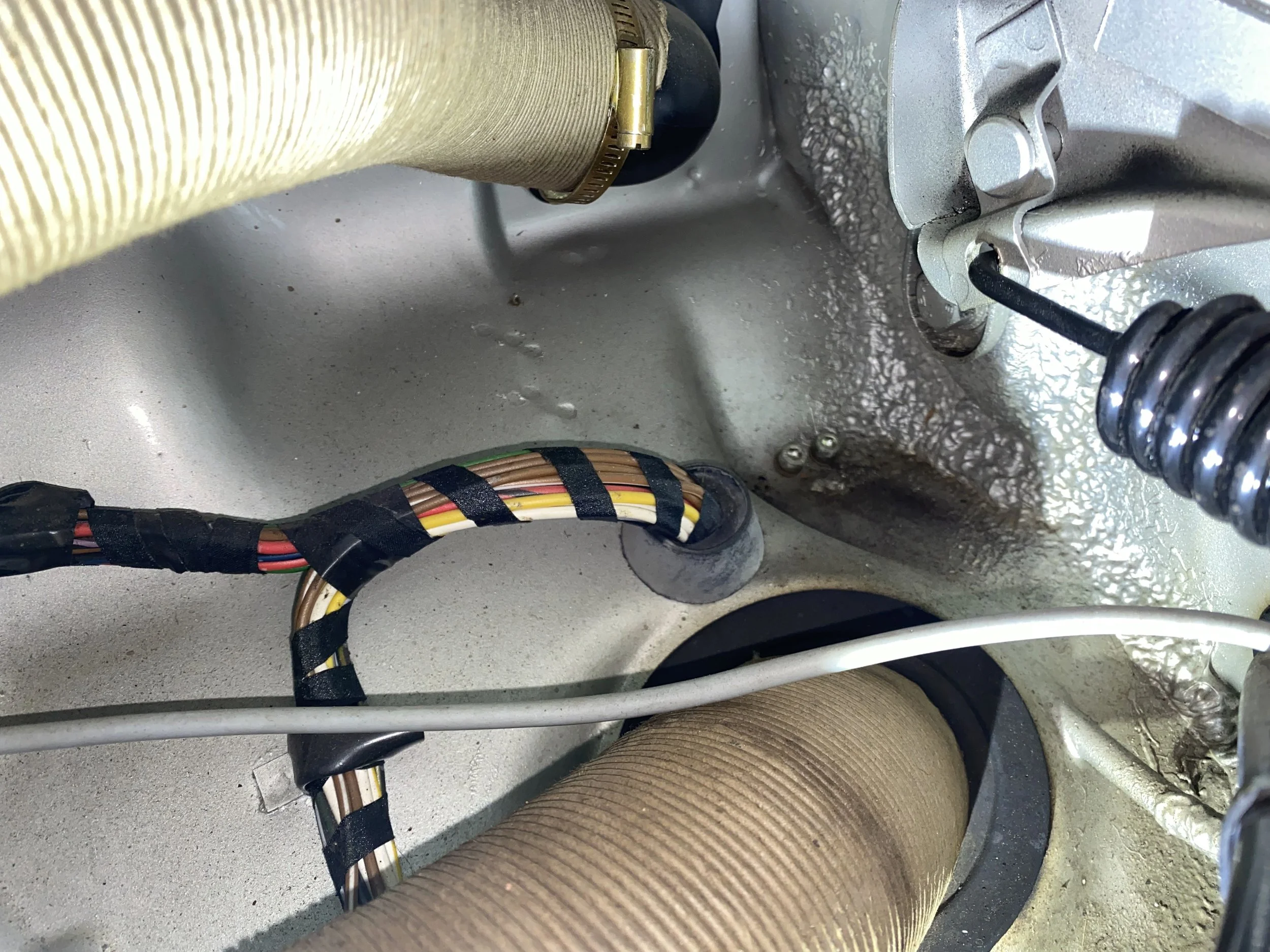 Close-up view of electrical wiring and mechanical components inside a Porsche 914. Visible insulated wires, metal parts, and tubing.