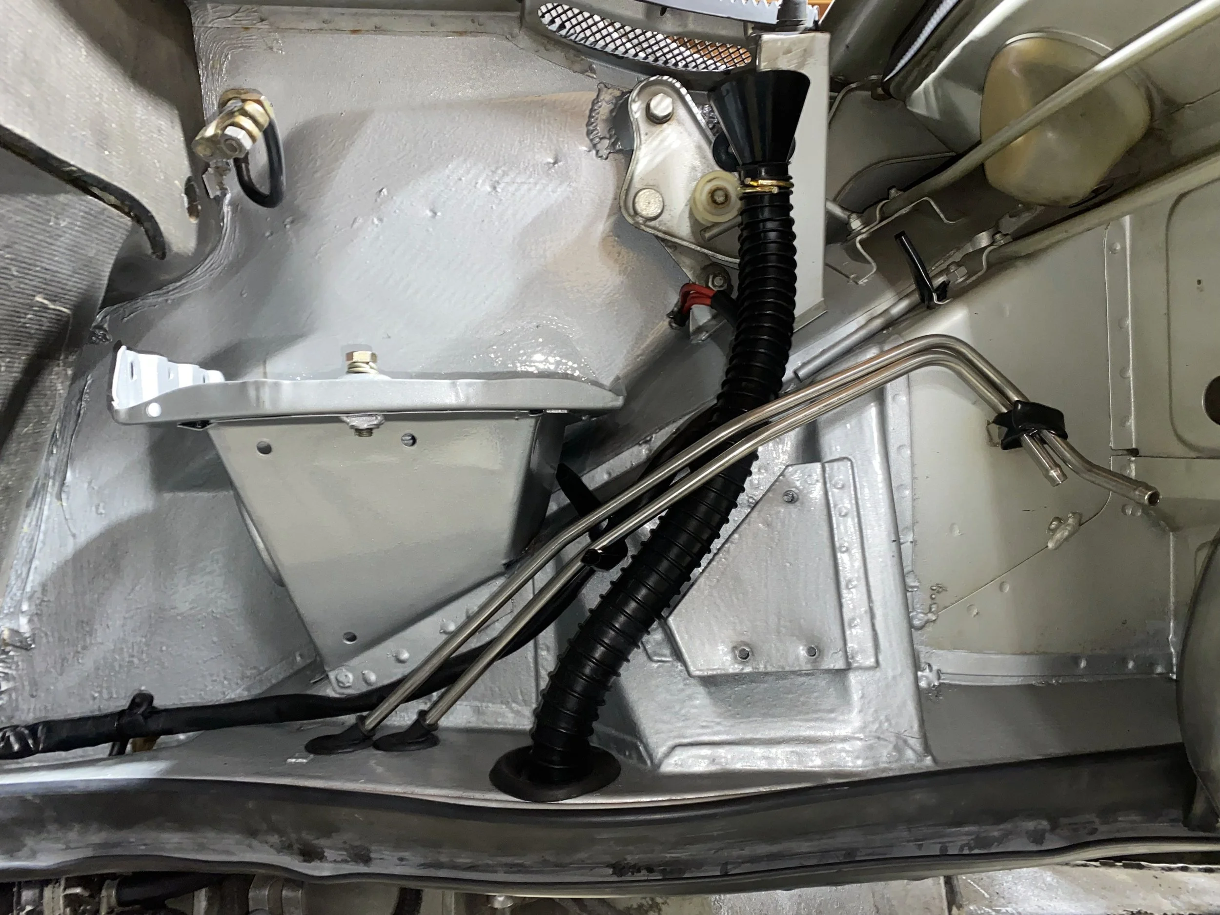 Close-up of a 914 underside with metallic components, black hoses, and various mechanical parts including tubes and screws.