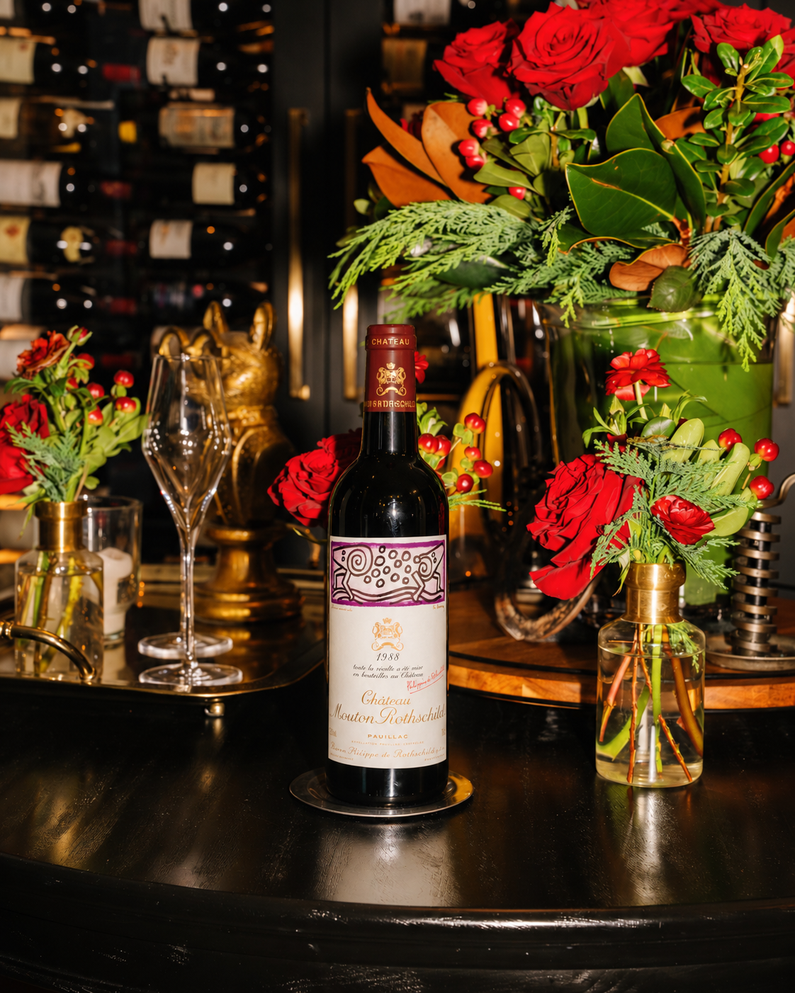 Chateau Mouton Rothschild 1988 Wine Bottle designed by Keith Harring  on a dark wood wine table surrounded by holiday florals at PARC Aspen