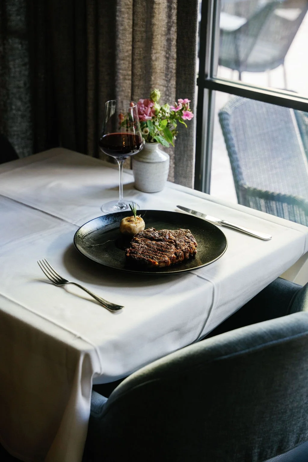 10 oz wagyu ribeye steak with garlic & rosemary served with a glass of red wine from PARC Aspen's award winning collection.