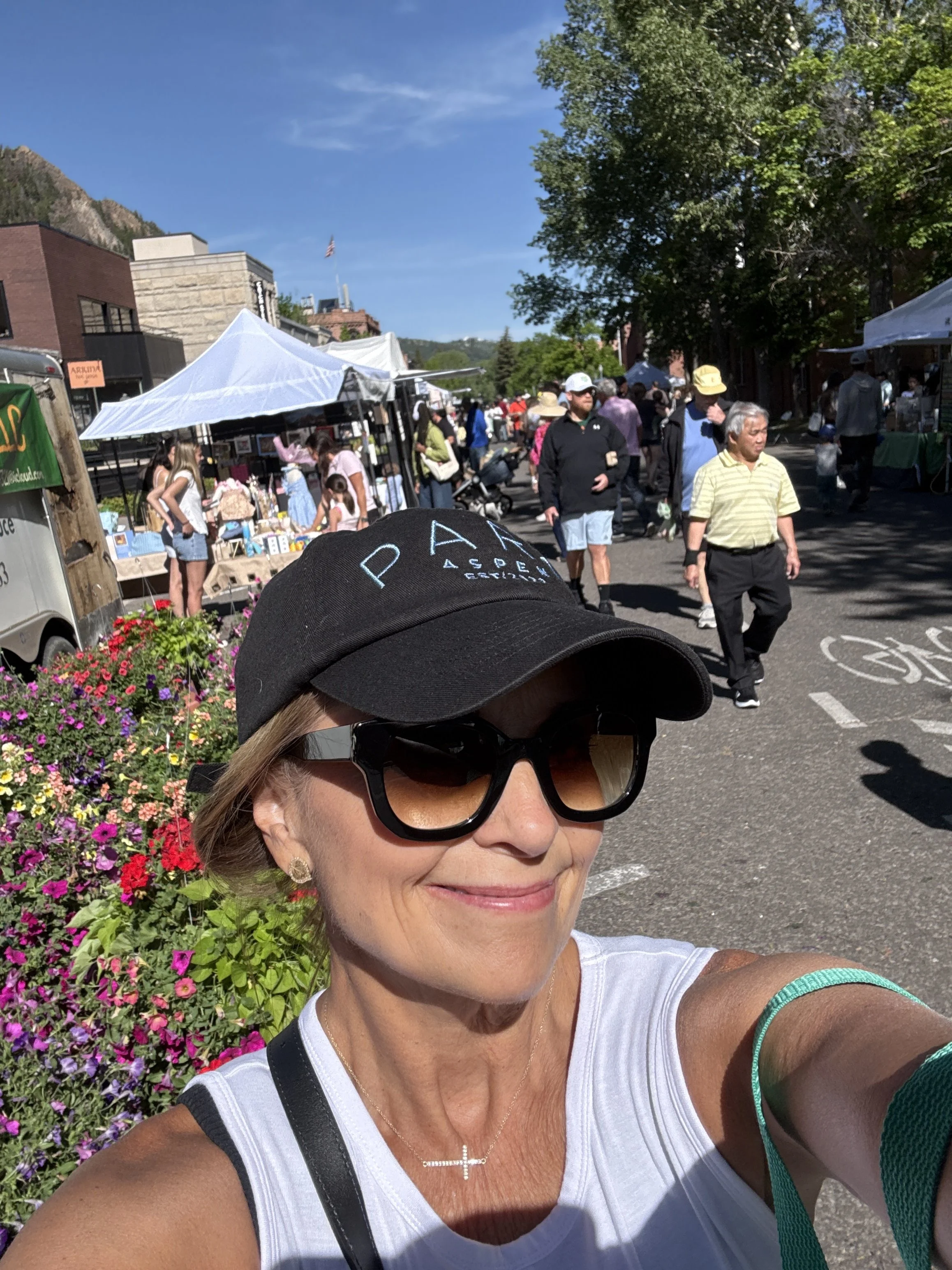 Woman wearing black ball cap with PARC Aspen logo while walking the farmers market.