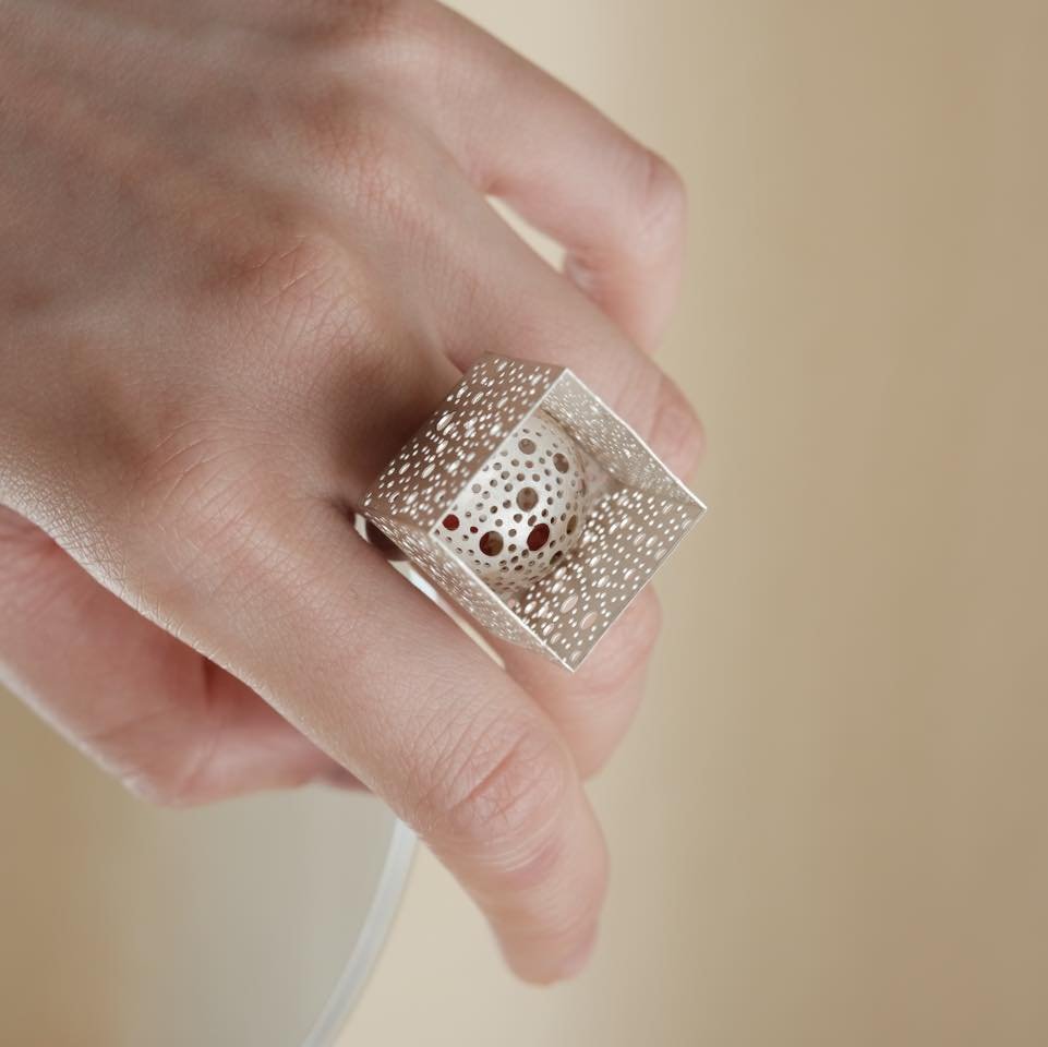 Square Cube Ring以簡約的幾何設計和巧妙的結構美學呈現，當光線穿透方塊的空隙，便如同樹蔭的影子映照在肌膚上，投下獨特的光影層次。戒指的空間感與線條在不同光源下展現微妙變化，讓佩戴者隨時隨地感受到光影之間的藝術對話，參與一場捕捉自然與光影的獨特體驗。

Square Cube ring features a minimalist geometric design with a unique structural aesthetic. When light passes through