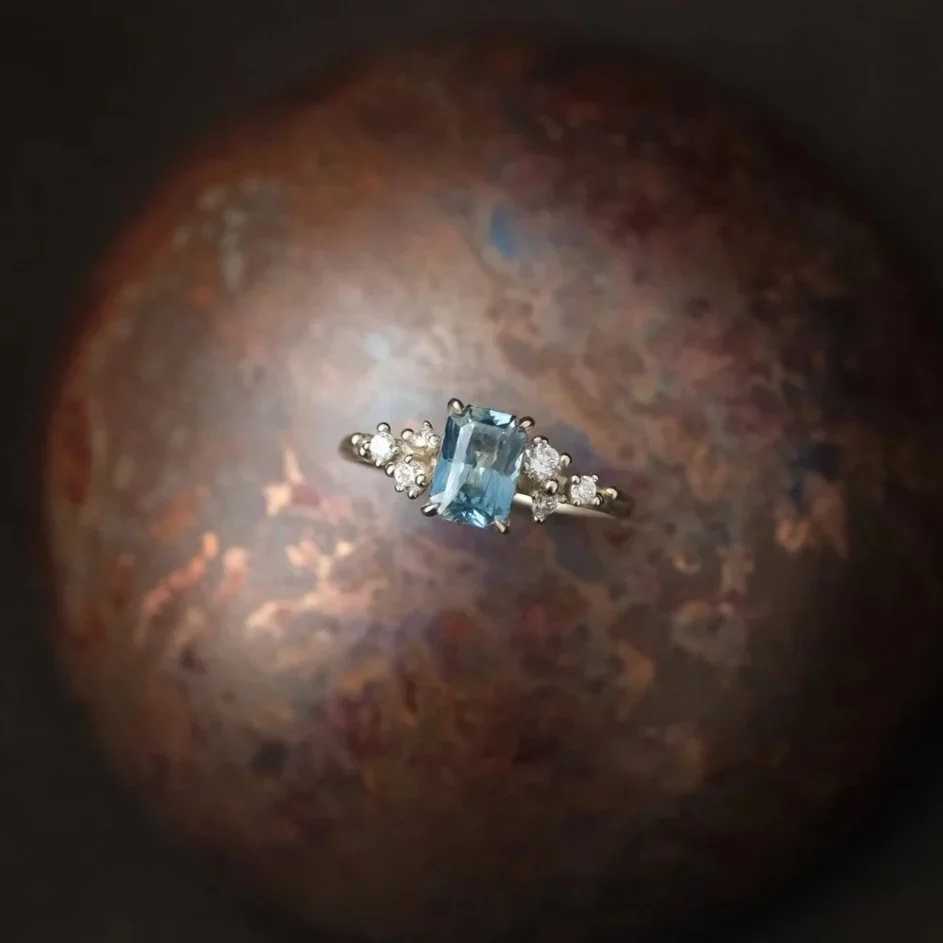 A ring with a large rectangular blue gemstone and small surrounding diamonds