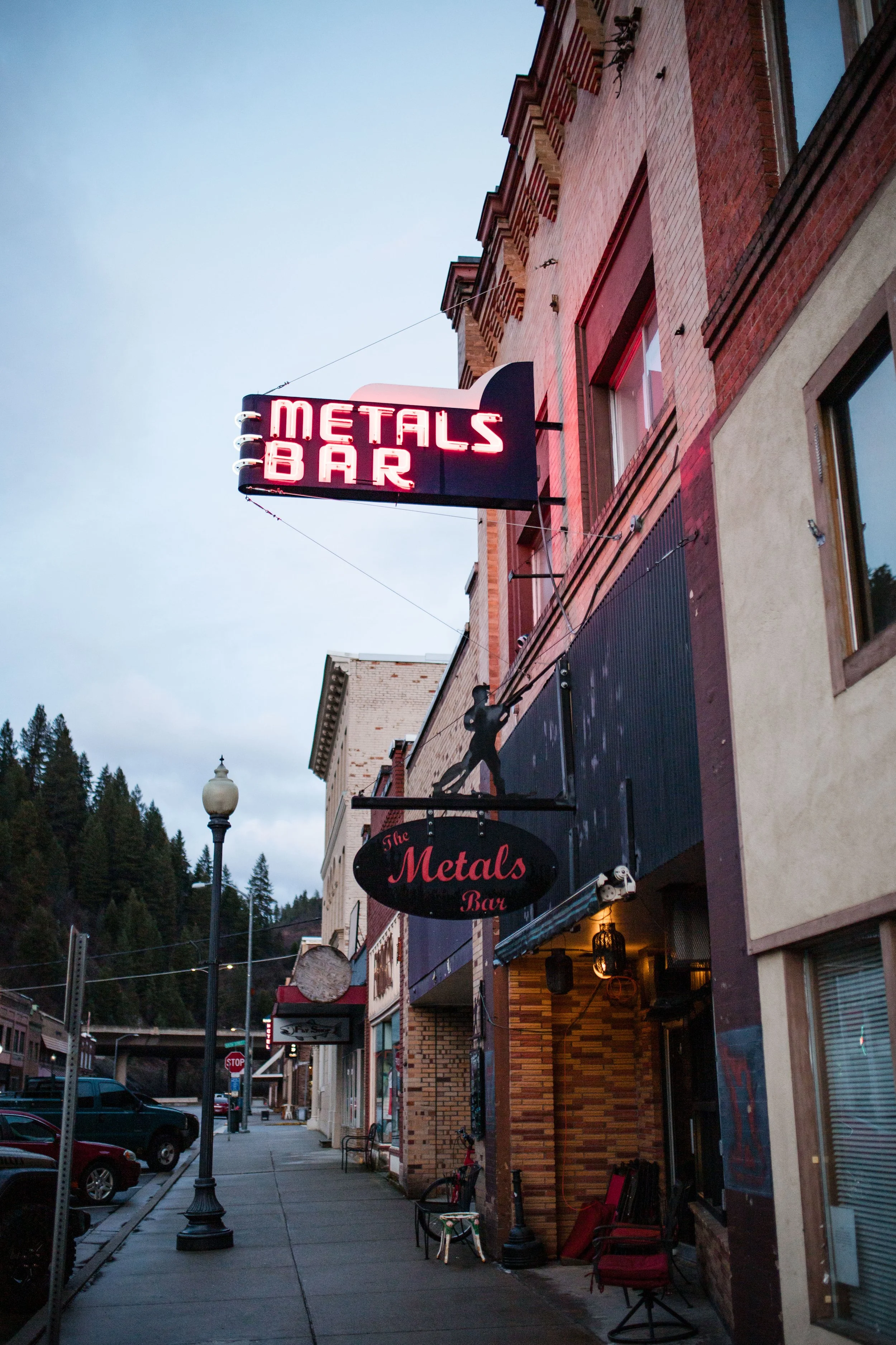 a neon sign that reads Metals Bar hanging over a historic brick building