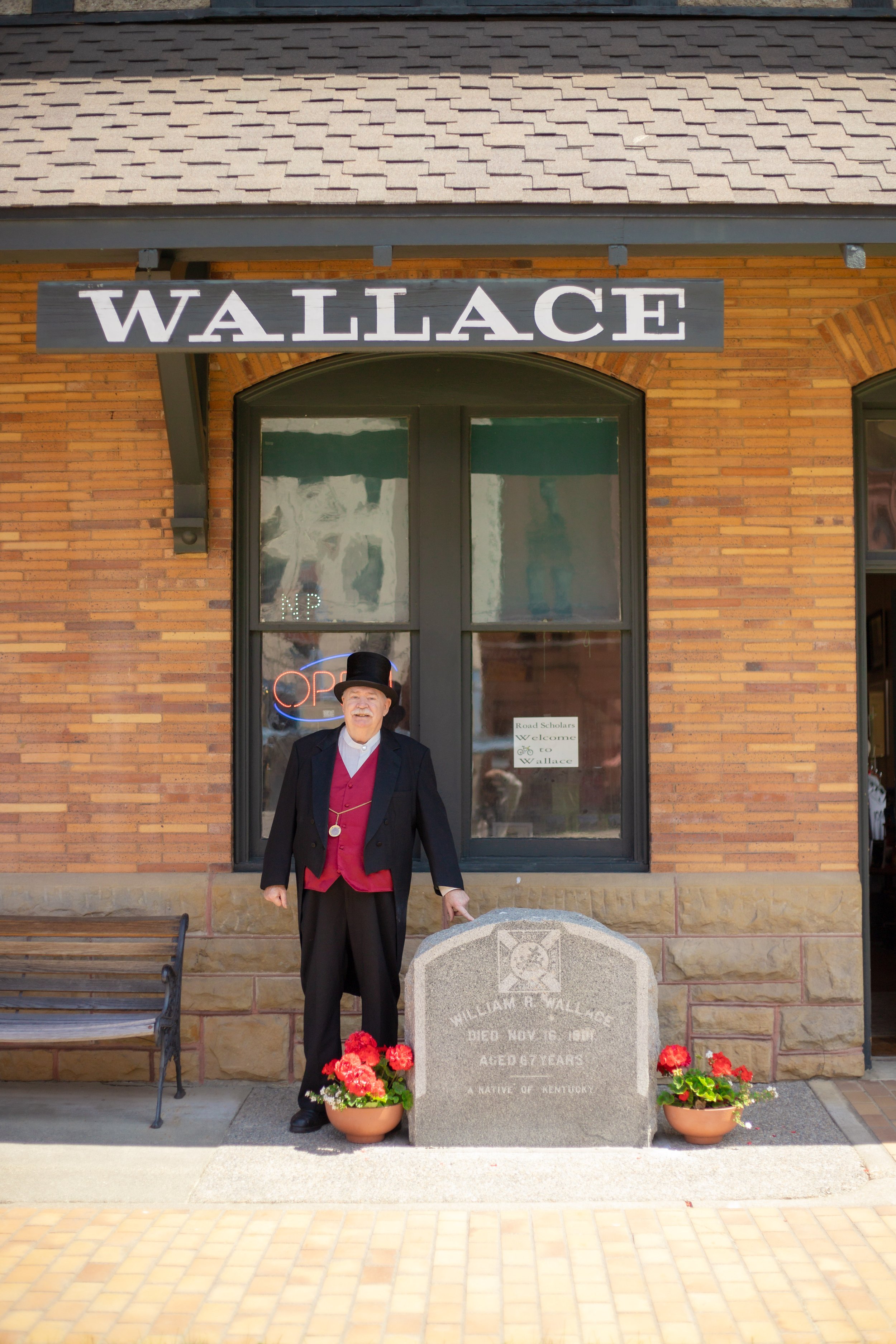 man in vintage suit standing outside of a museum with a sign that says Wallace above him