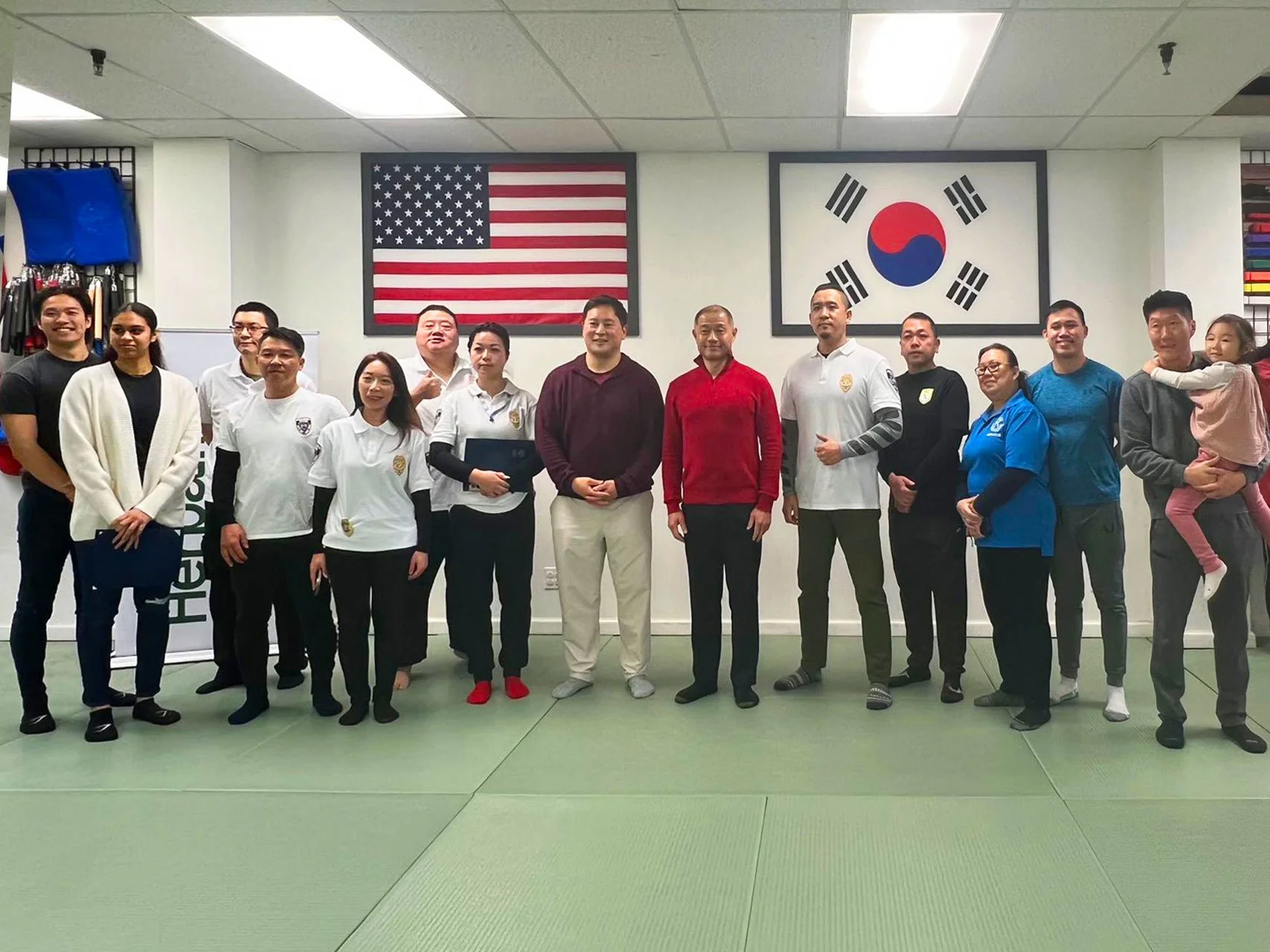 Instructors and students gather for a group photo in a martial arts studio during a professional Self Defense Class.
