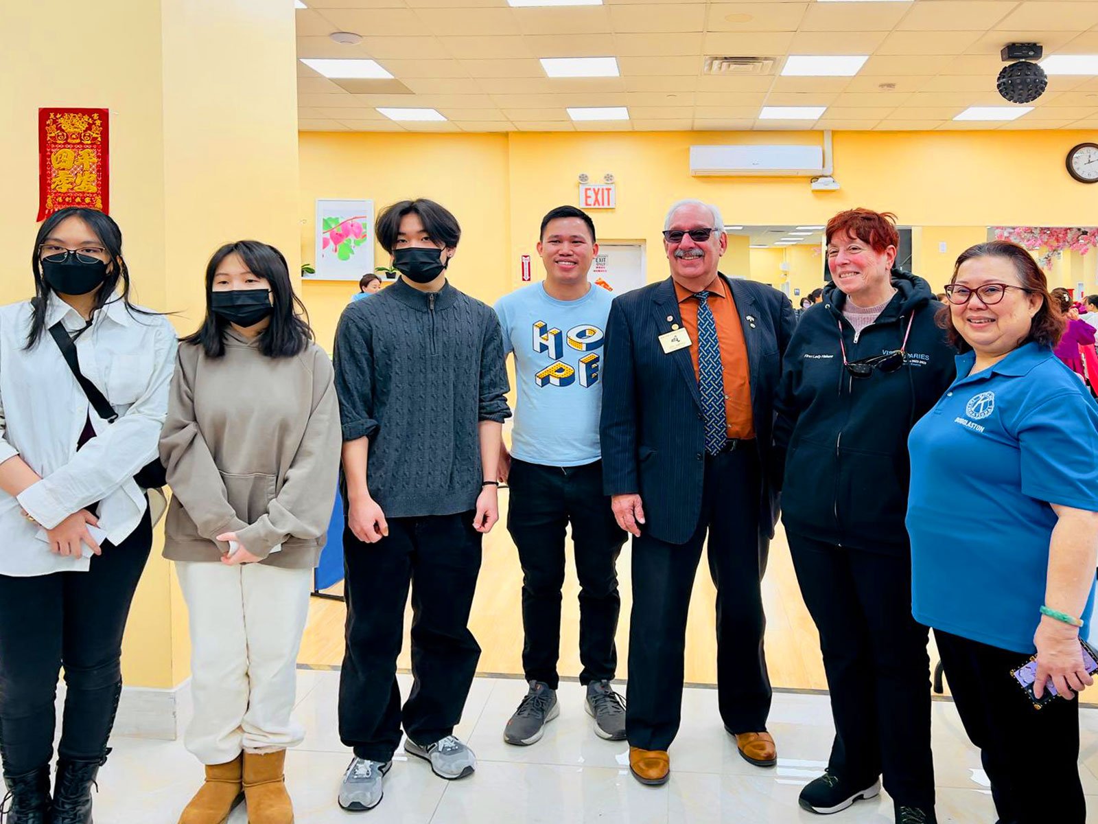 A diverse group of people posing together at a local event, showcasing the unity of a vibrant and strong community.