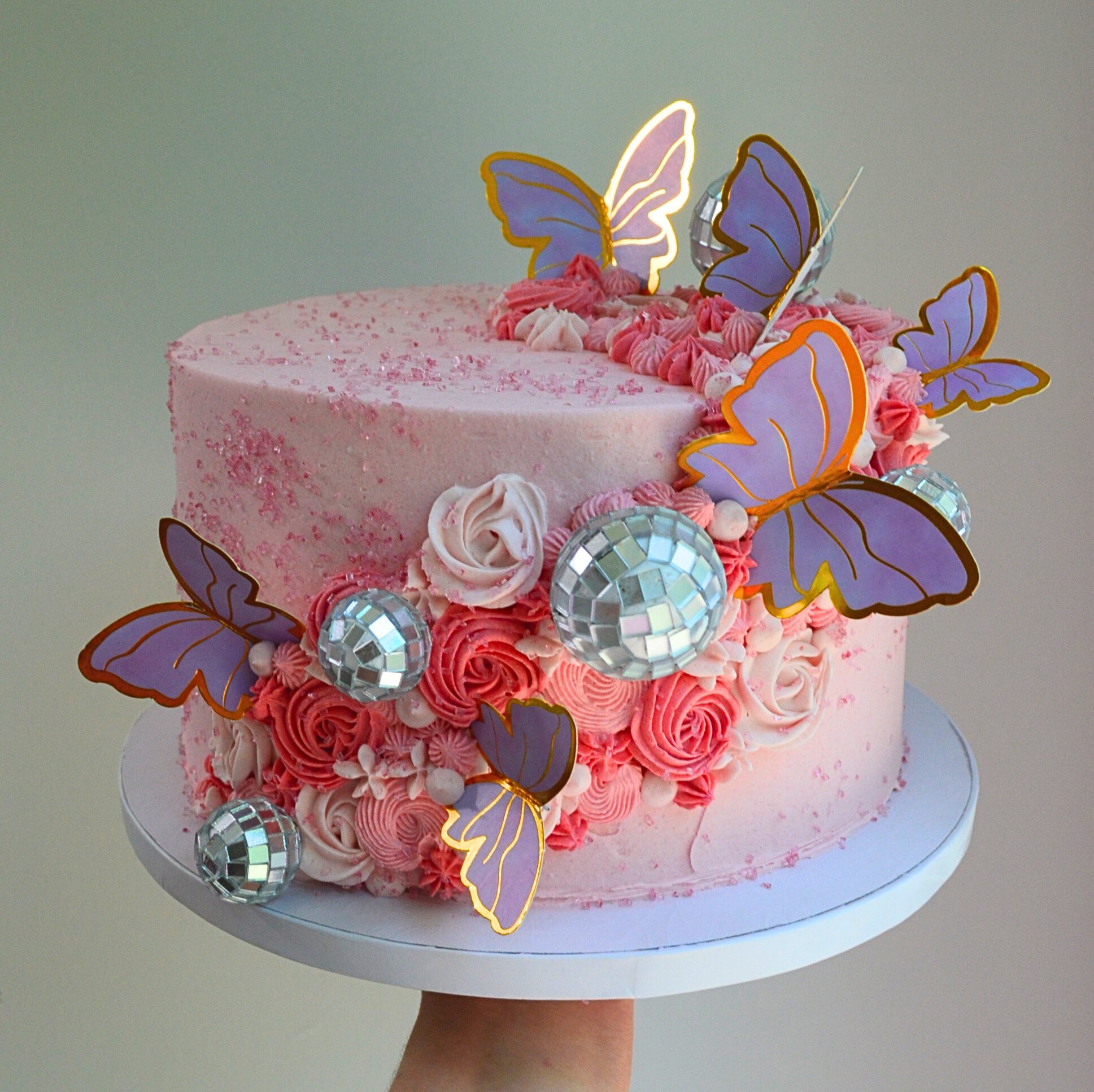 #3. Pink cake decorated with swirls in multiple shades of pink, disco balls, pink sugar sprinkles and butterflies.