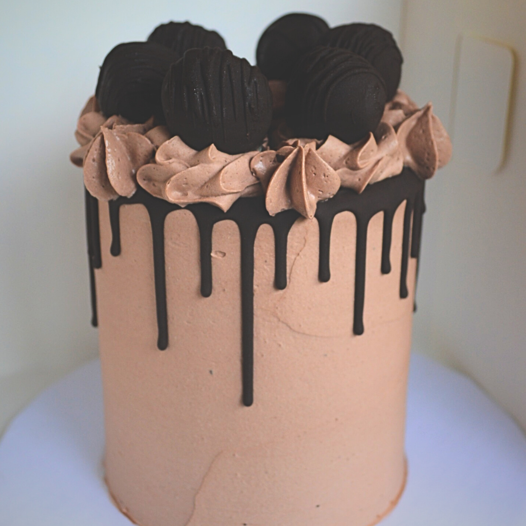 #119. This is a 4" round, 3-layer triple chocolate cake with a dark chocolate drip and chocolate truffles.