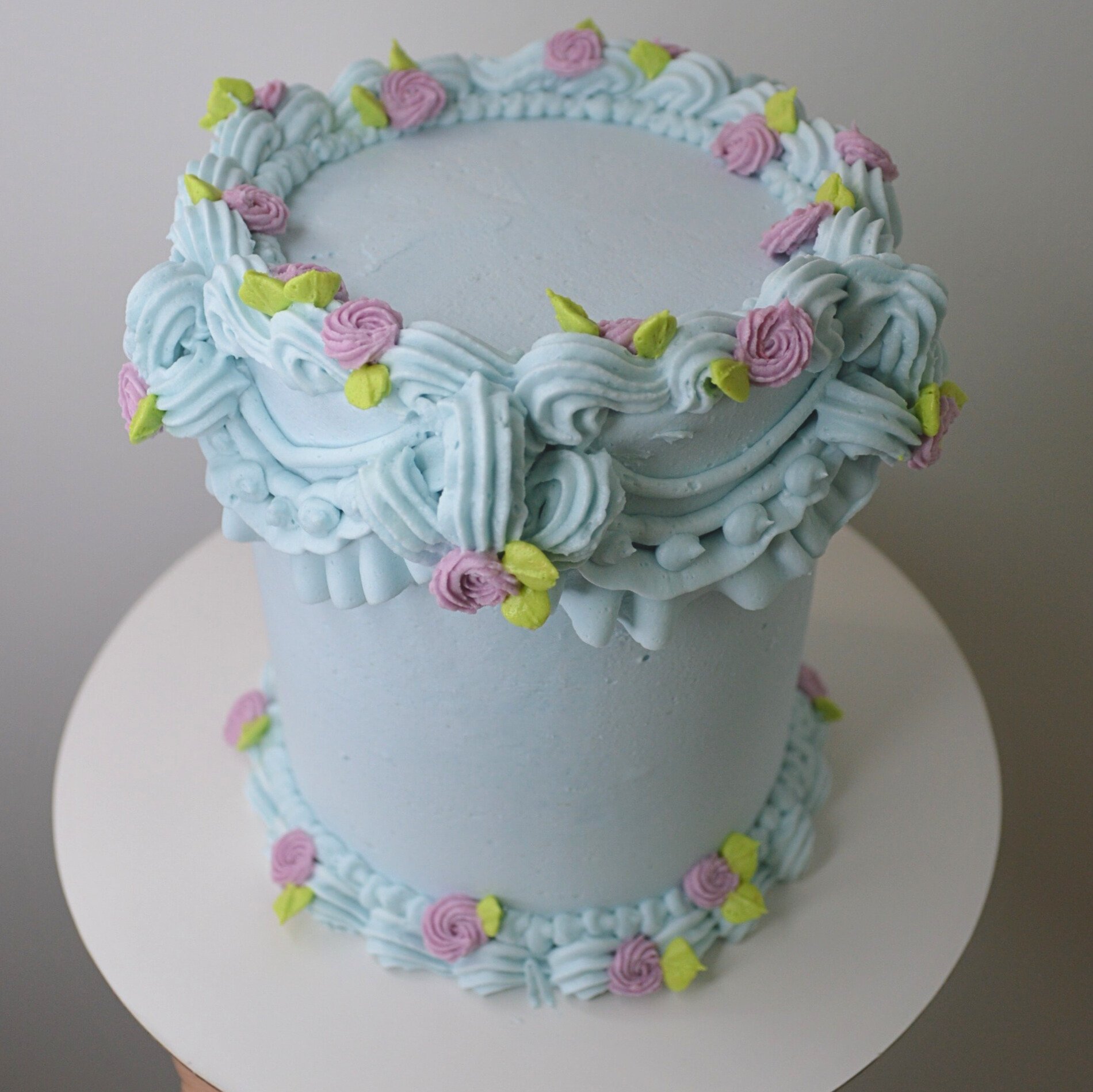 #4. Light blue vintage cake with pink frosting rosettes and piped green leaves.