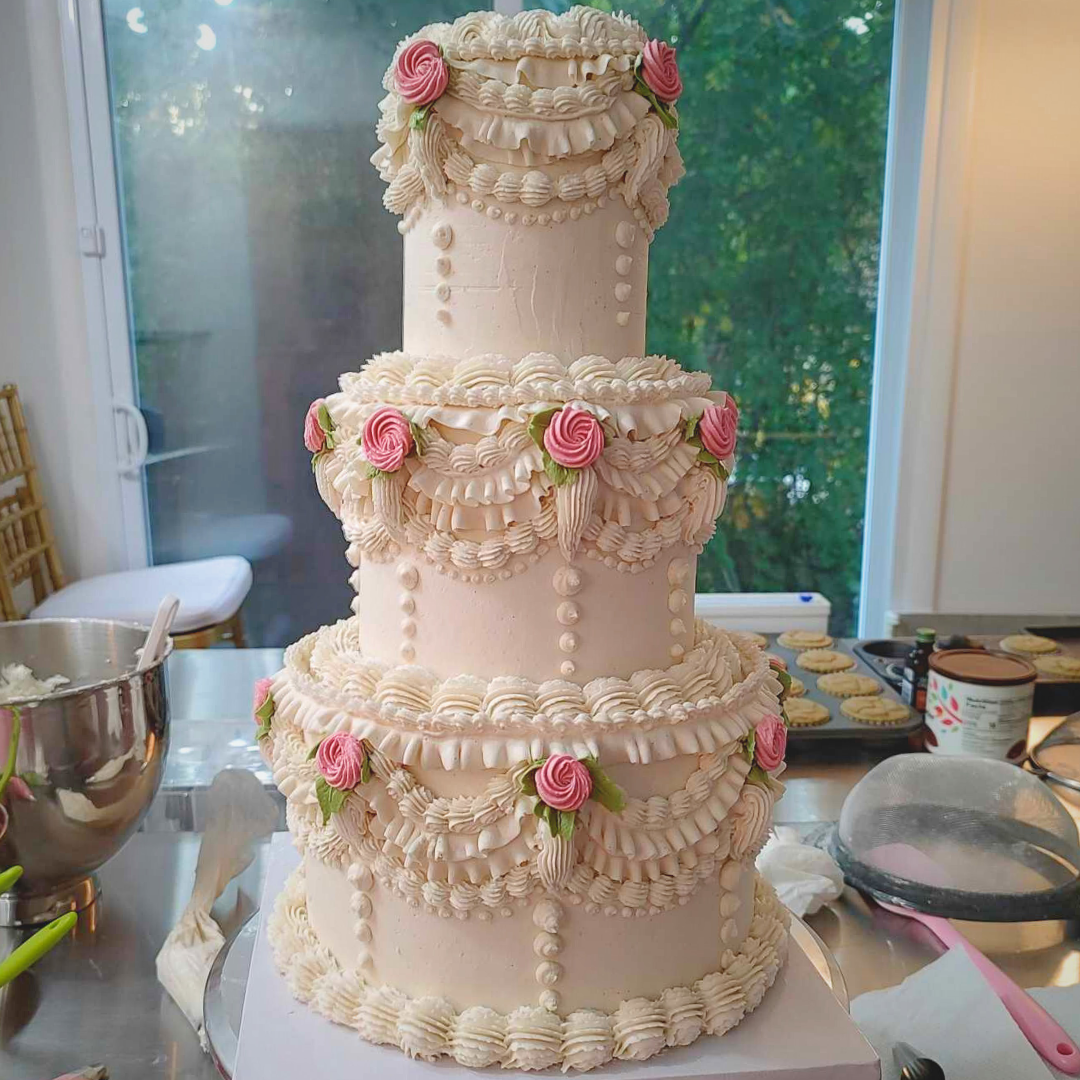 #112. This is a three-tiered vintage style wedding cake with hand-piped frosting rosettes and leaves. The sizes of the tiers are a 10" round, 4-layer tier on the bottom, then an 8" round, 4-layer, then a 6" round, 4-layer tier.