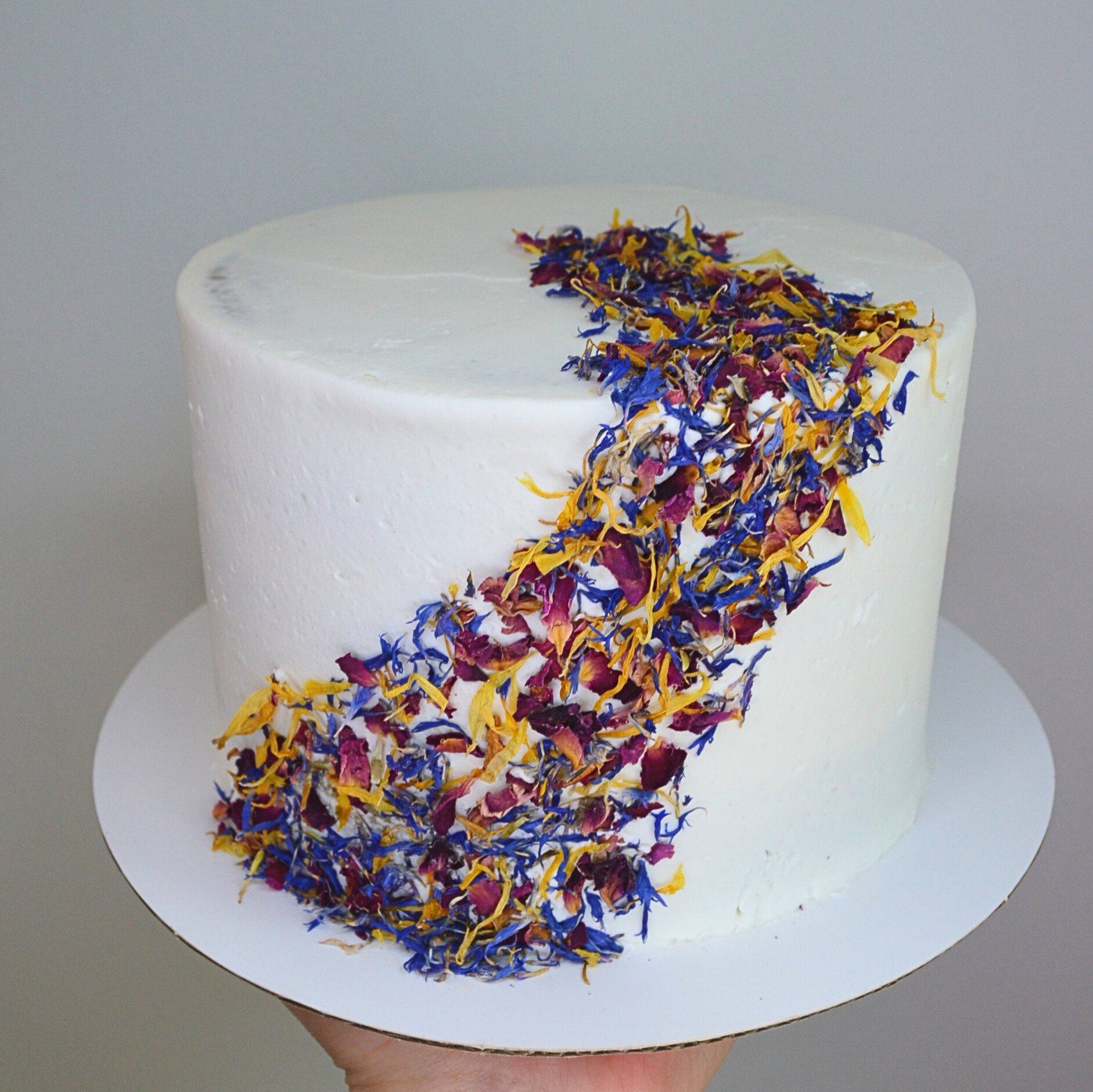 #29. Smoothly frosted cake with a diagonal design of edible flower petals.