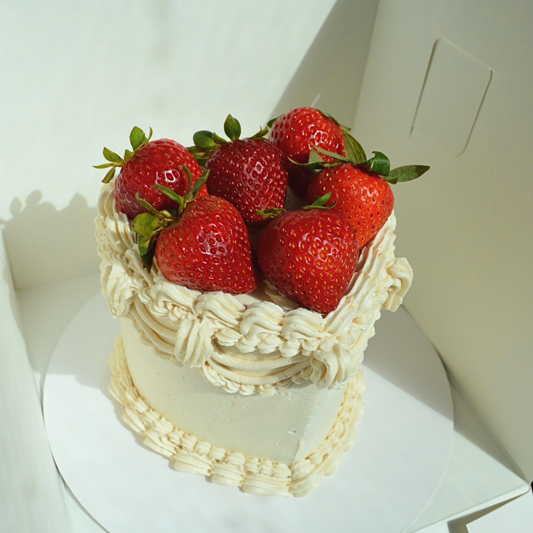 #21. Small, heart-shaped vintage style cake with fresh strawberries on top.