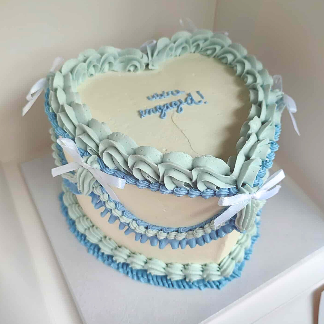 #102. This is an 8" heart-shaped, 3-layer vintage style cake with ribbon bows.