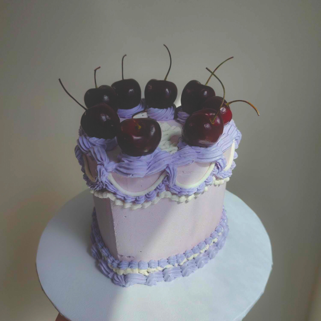 #113. This is a 4" heart-shaped , 3-layer multi-colored vintage cake with fresh cherries on top.