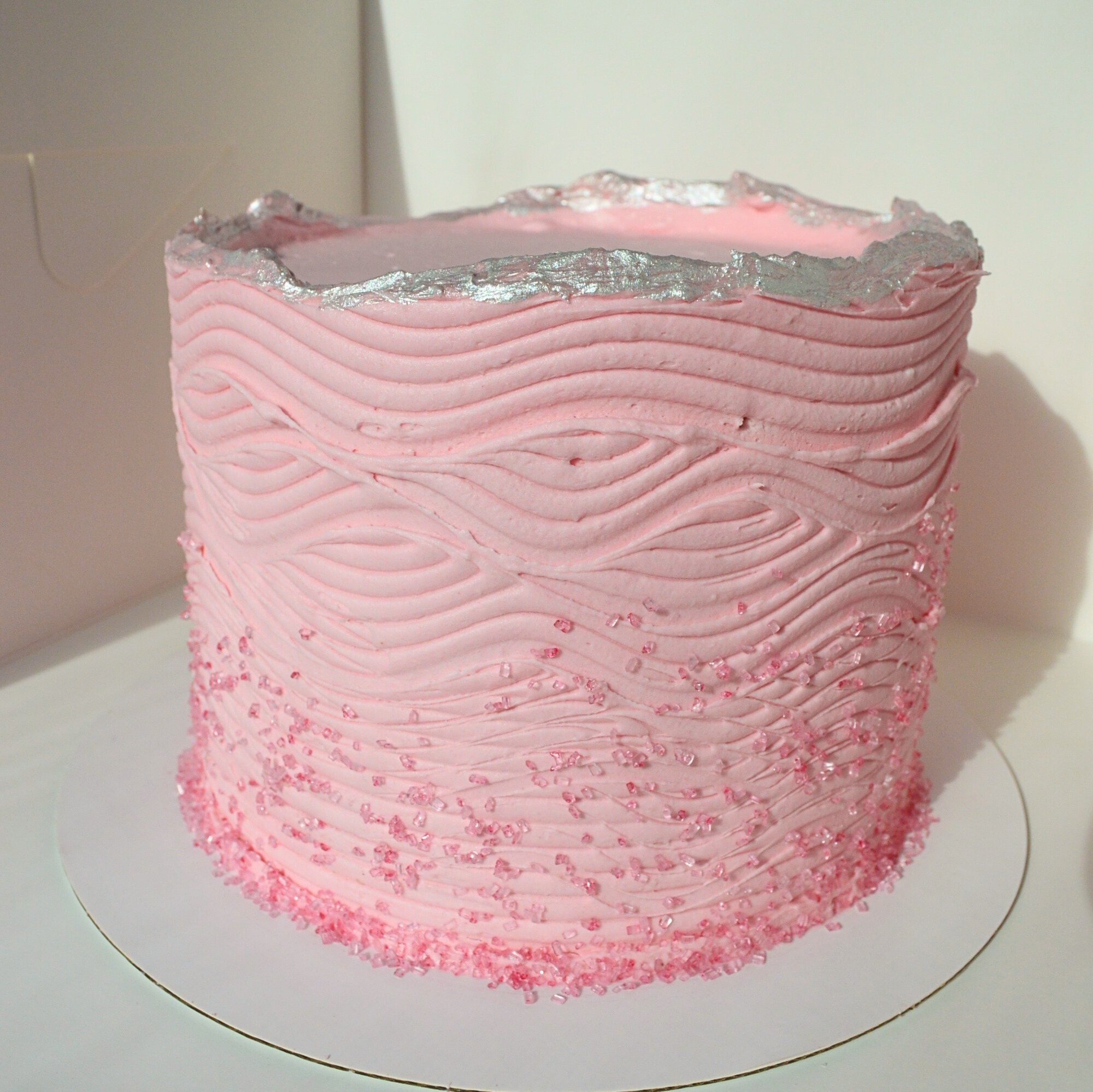 #16. Pink cake with a wave texture, pink sugar sprinkles, and edible silver paint painted on a natural top ridge.