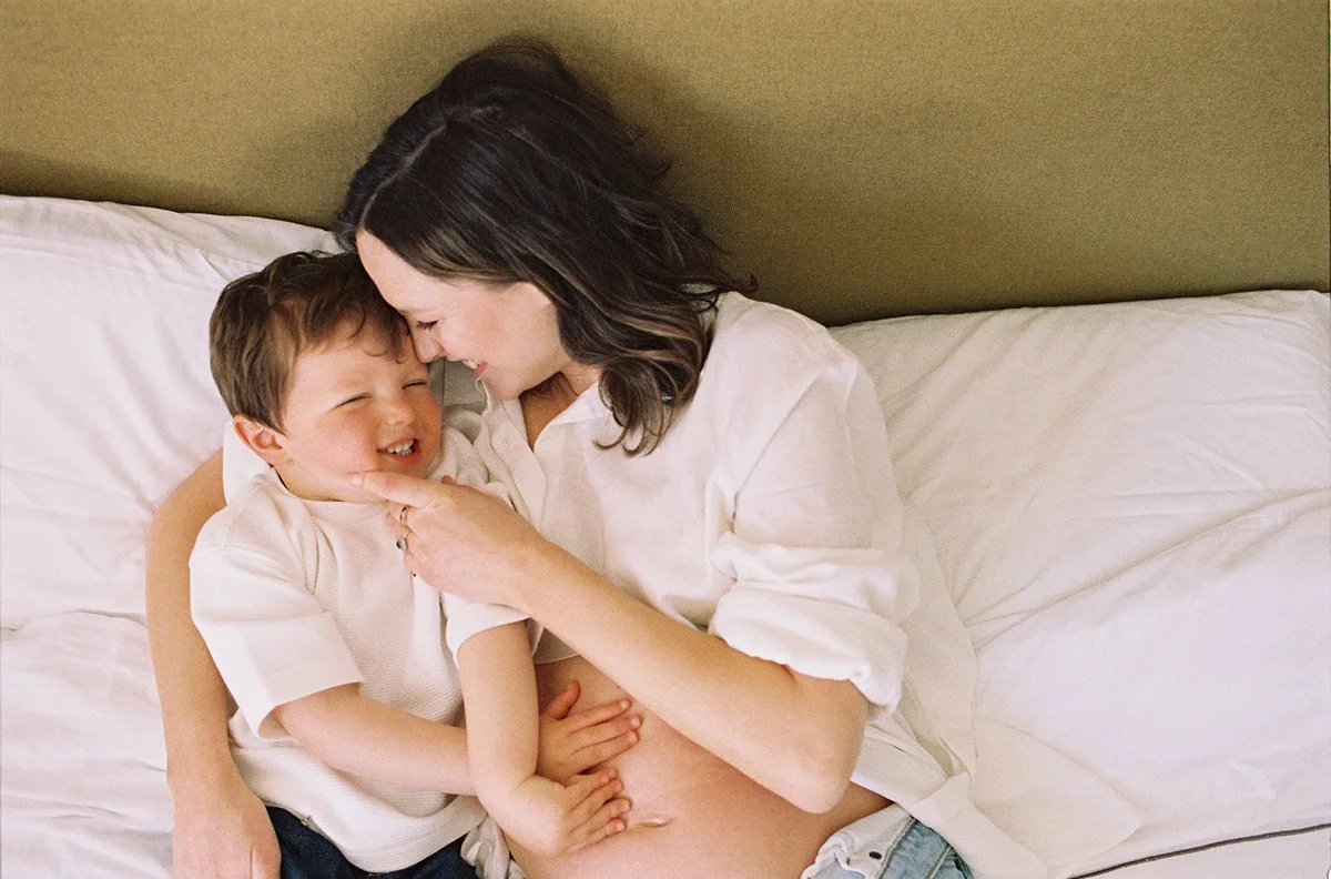 Colour photo of a Mum-to-be and her young son at home in bed