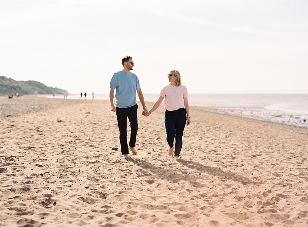 portrait of parents walking hand in hand along the beach