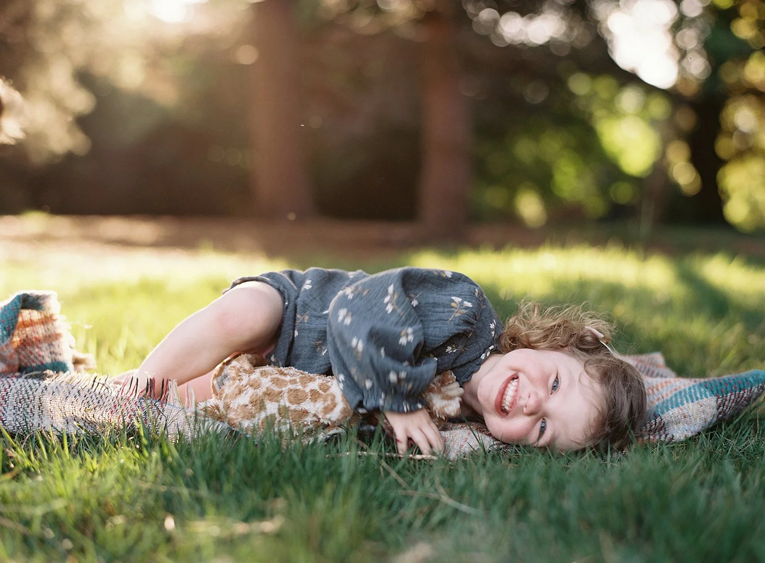 Portrait of a little girl lying on the grass and smiling in the evening light captured on film